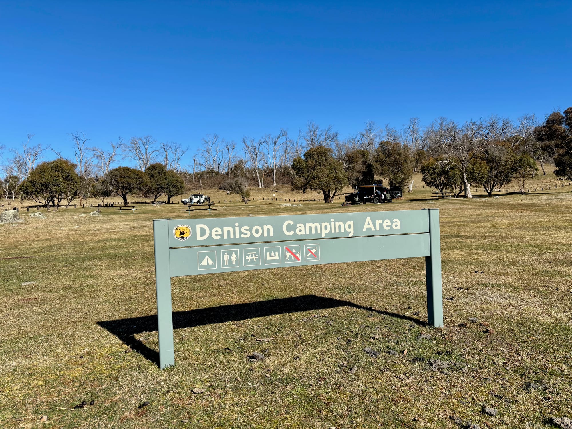 The Denison Camping Area sign showing camping, toilets, picnic tables and fireplaces, and no dogs