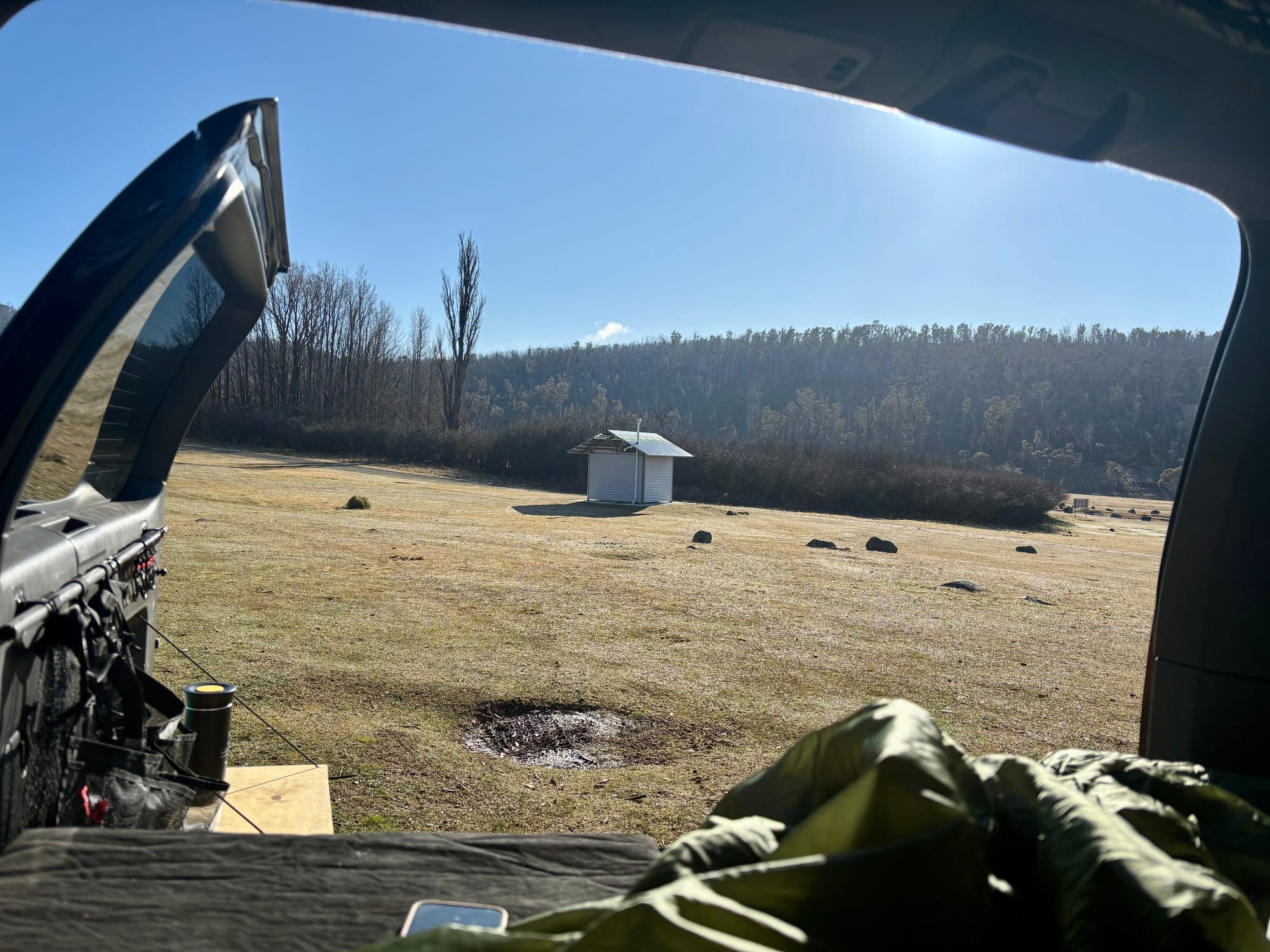 The view from the back of our 4WD in the morning, over the grass to the toilet block and the hills