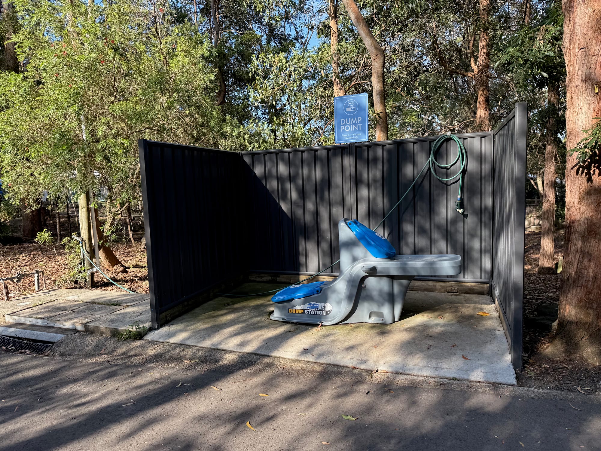 The dump point at Discovery Parks Lane Cove: a blue and grey dump station with a hose inside a dark screen, under a Dump Point sign
