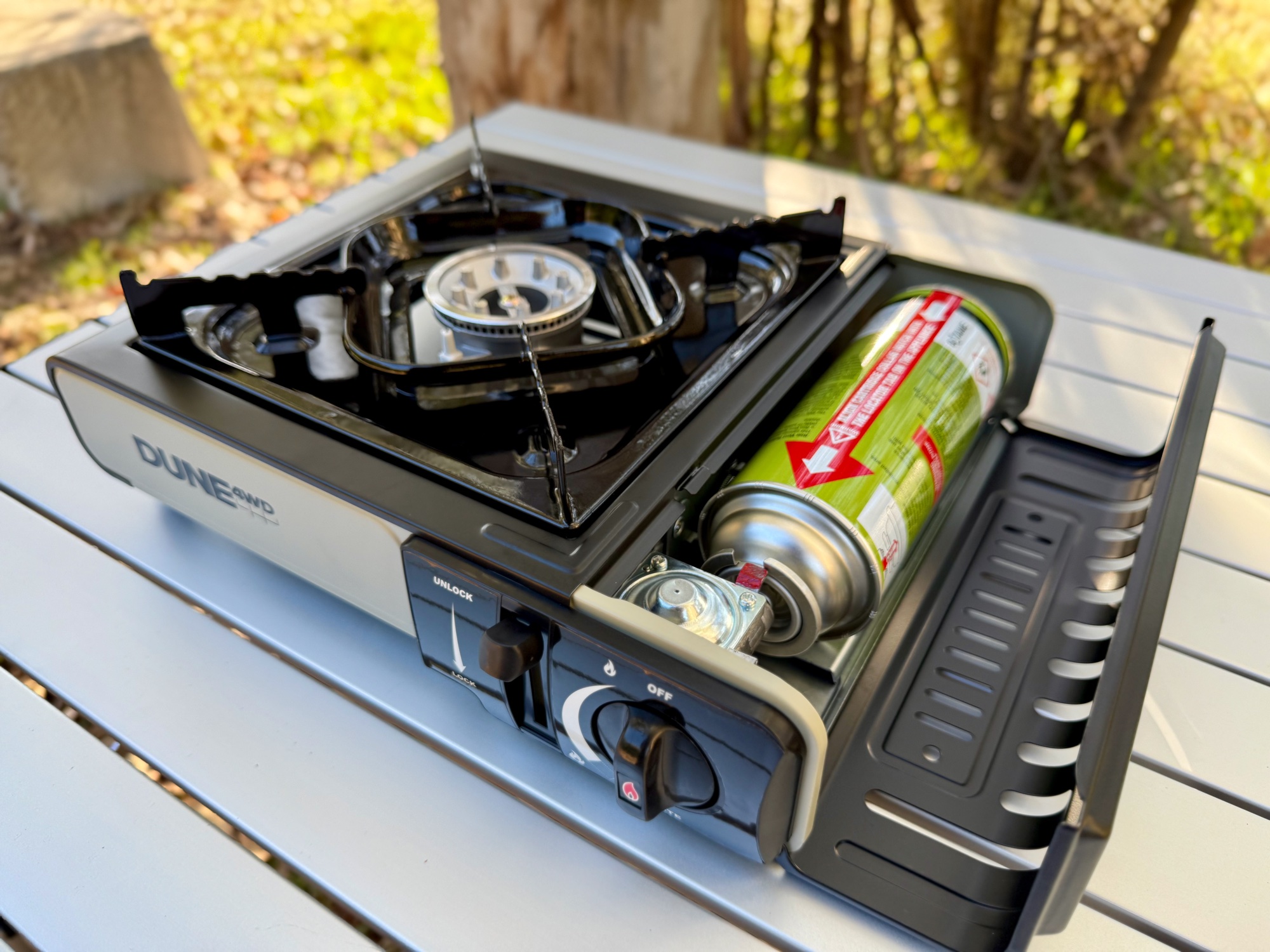 A butane canister loaded into the Dune 4WD stove with the lid open