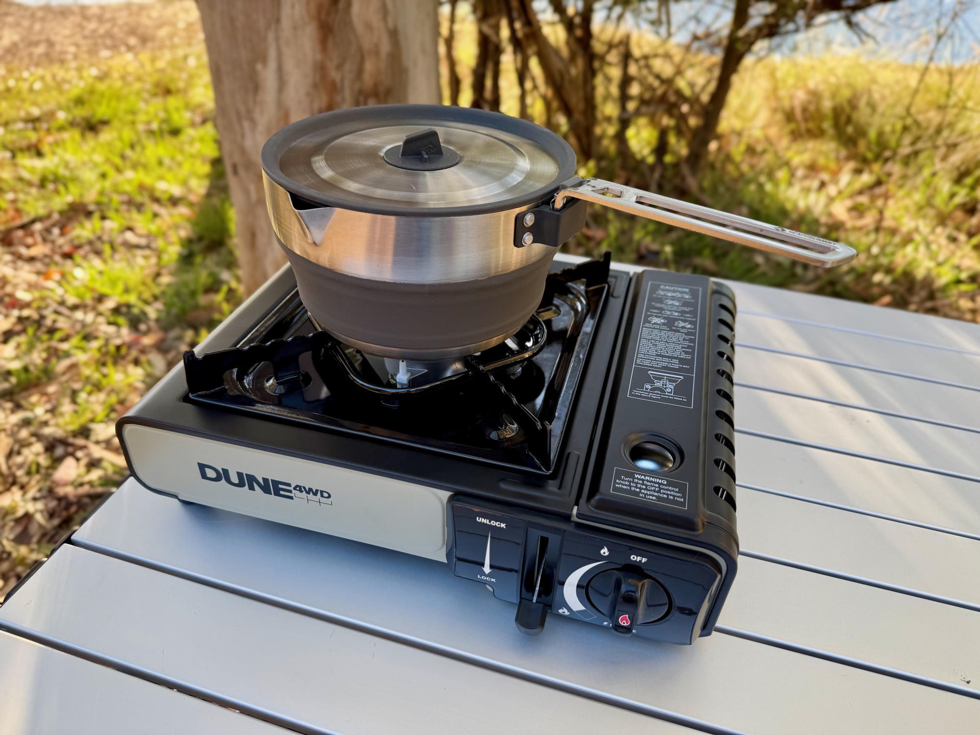 A pot on the Dune 4WD single burner stove on a camp table by the water