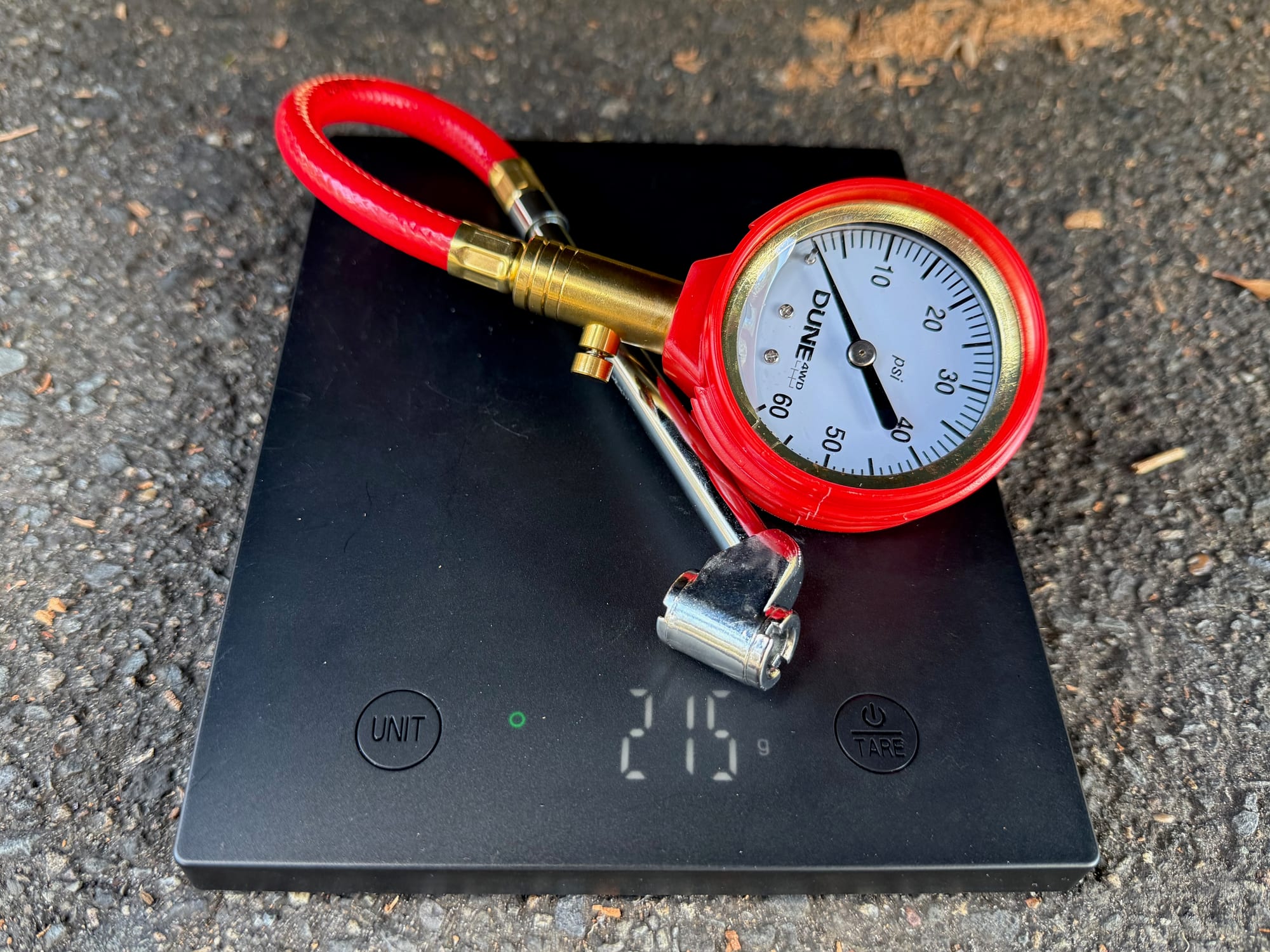 The Dune 4WD Tyre Pressure Gauge on a scale showing 215 g