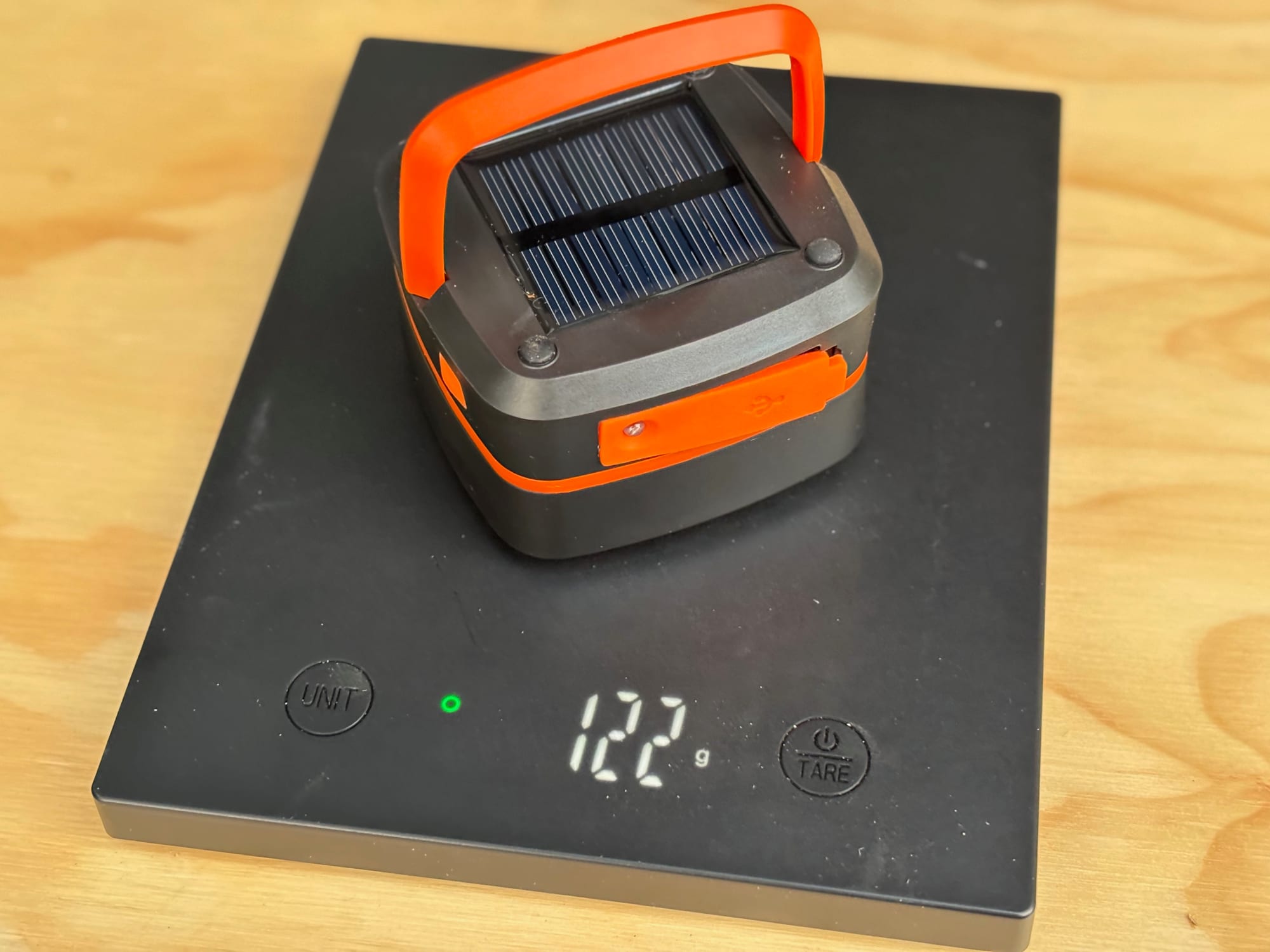 The folded solar lantern on a digital scale showing 122 grams