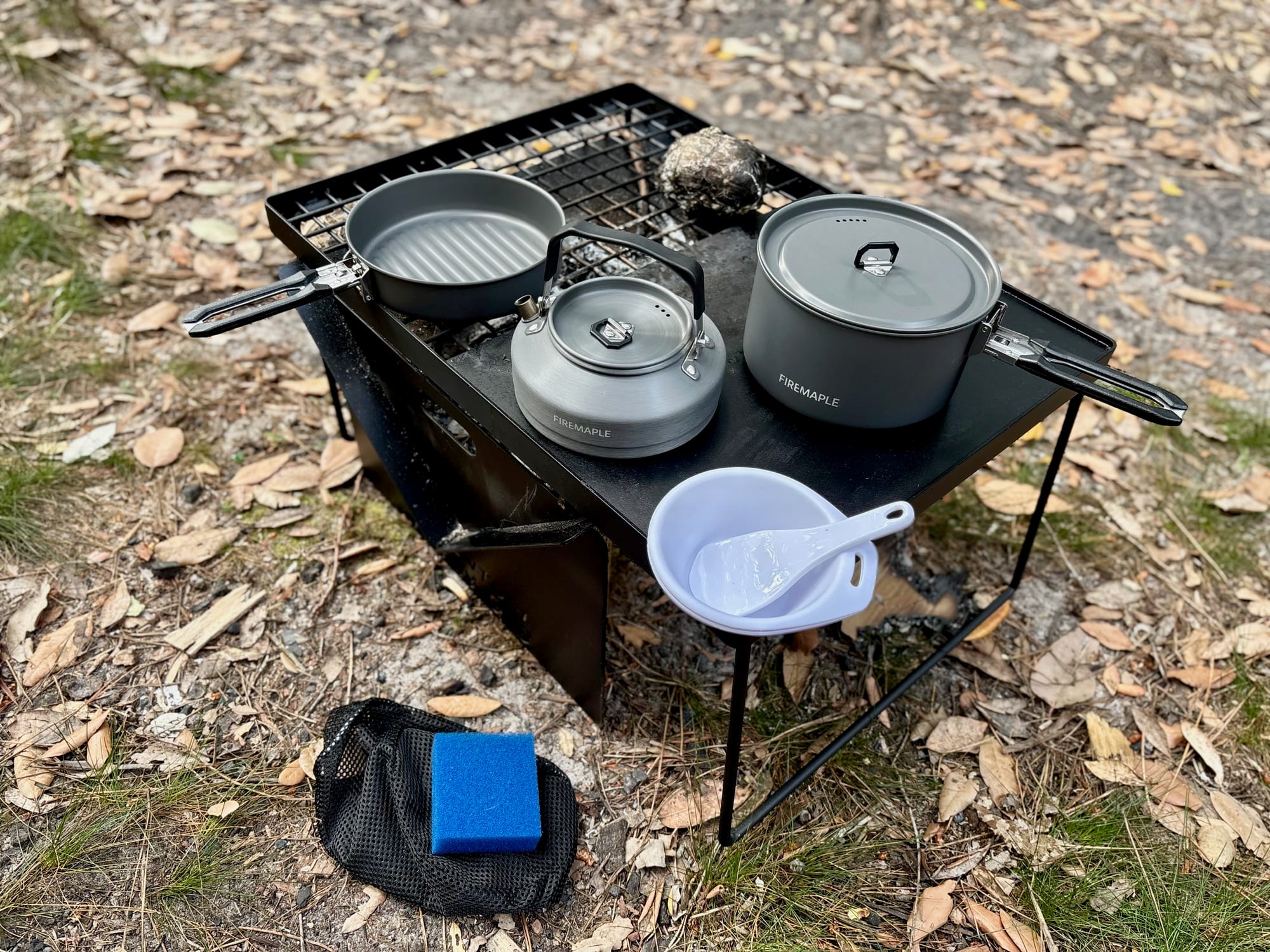 Everything in the Firemaple Feast 2 set laid out: pot, frypan, kettle, bowl, scoop, sponge and mesh bag
