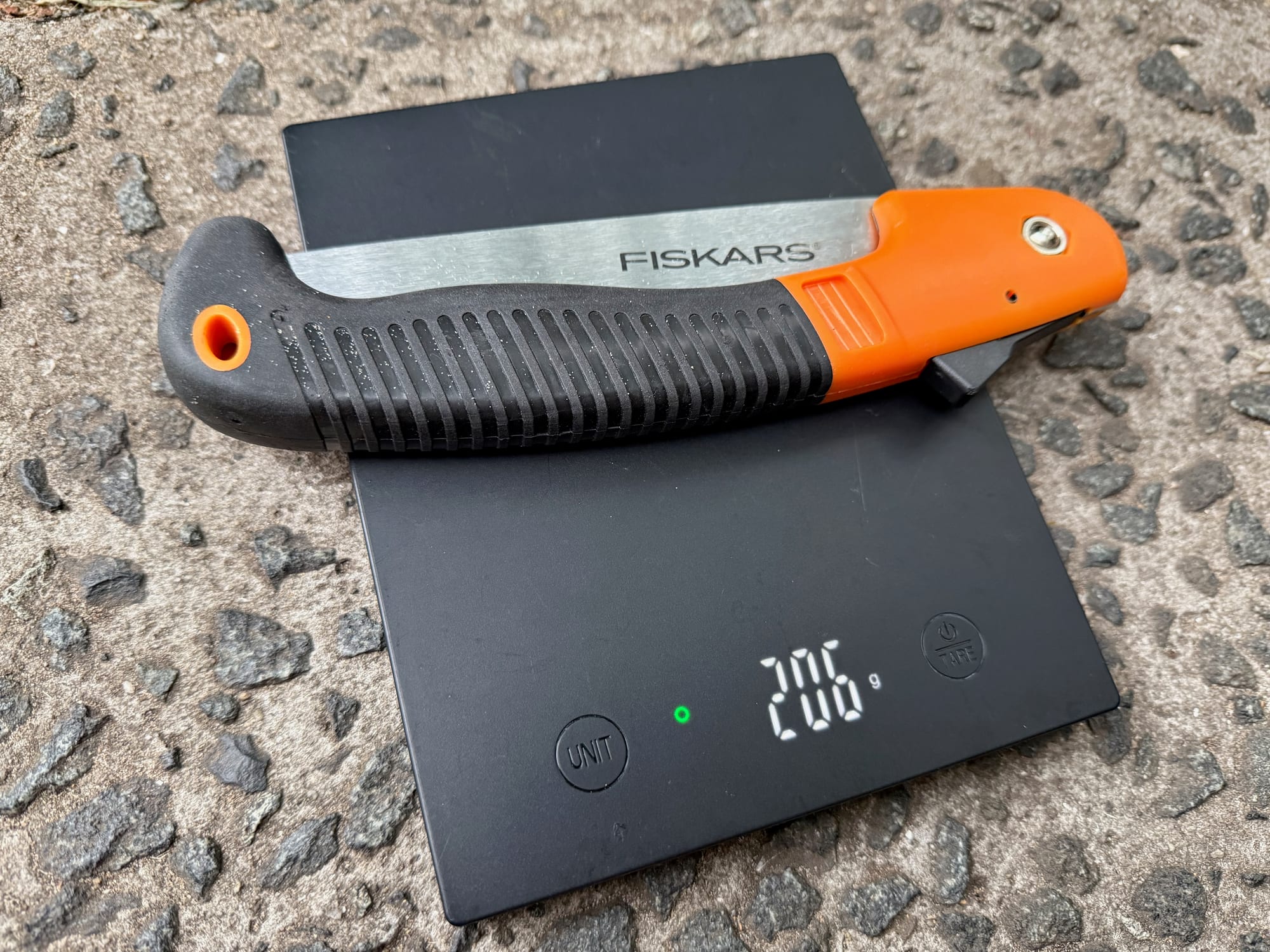 The Fiskars 7-inch saw on a kitchen scale showing 206 g