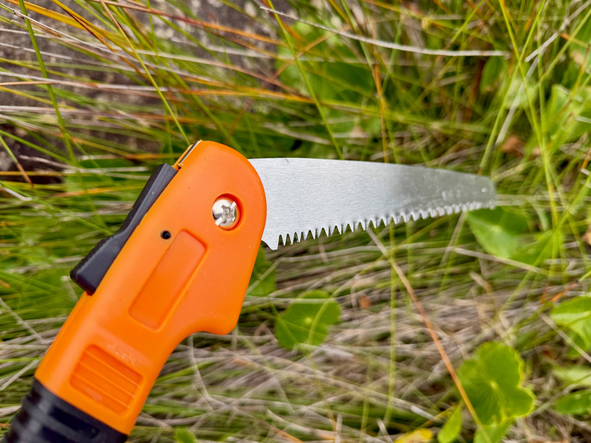 The orange head of the Fiskars saw with the pivot bolt and the black lock lever
