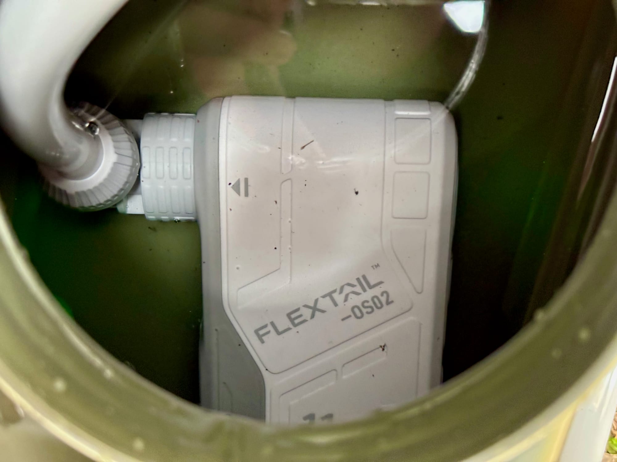 The FlexTail Max Shower pump sitting under water inside a green jerry can