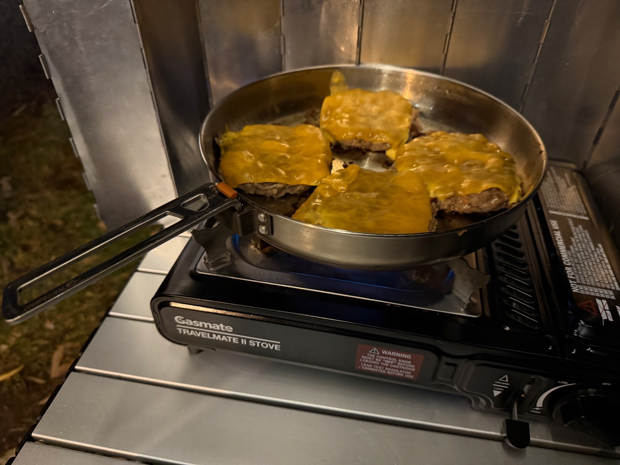 Cheeseburger patties in a frying pan on the Gasmate Travelmate II