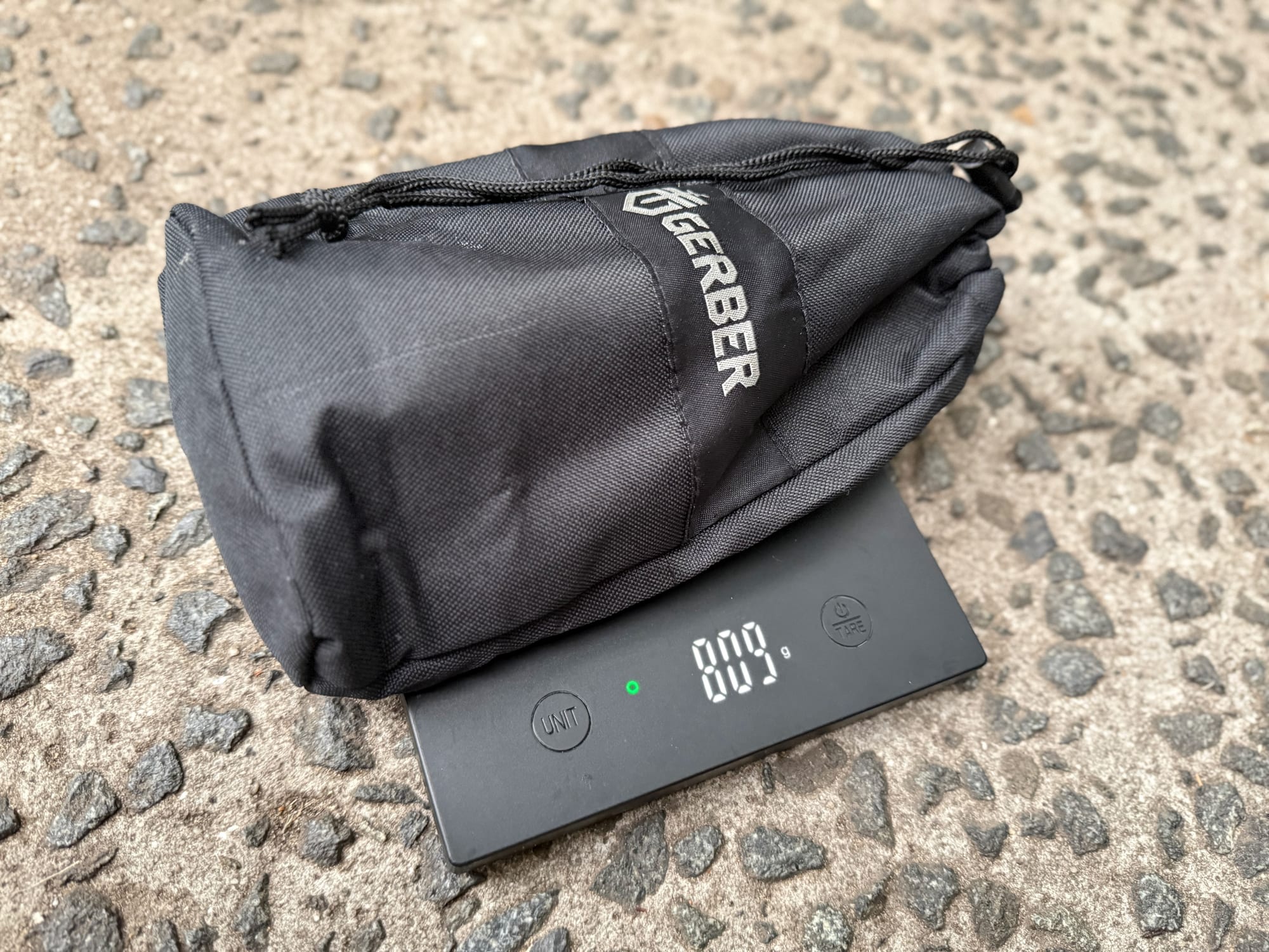 The Gerber Gorge folding shovel in its drawstring bag on a scale showing 809 g