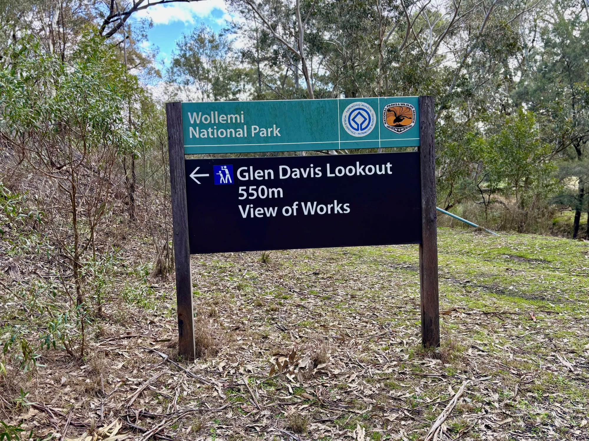 The Wollemi National Park sign pointing to Glen Davis Lookout, 550 m, with a view of the works