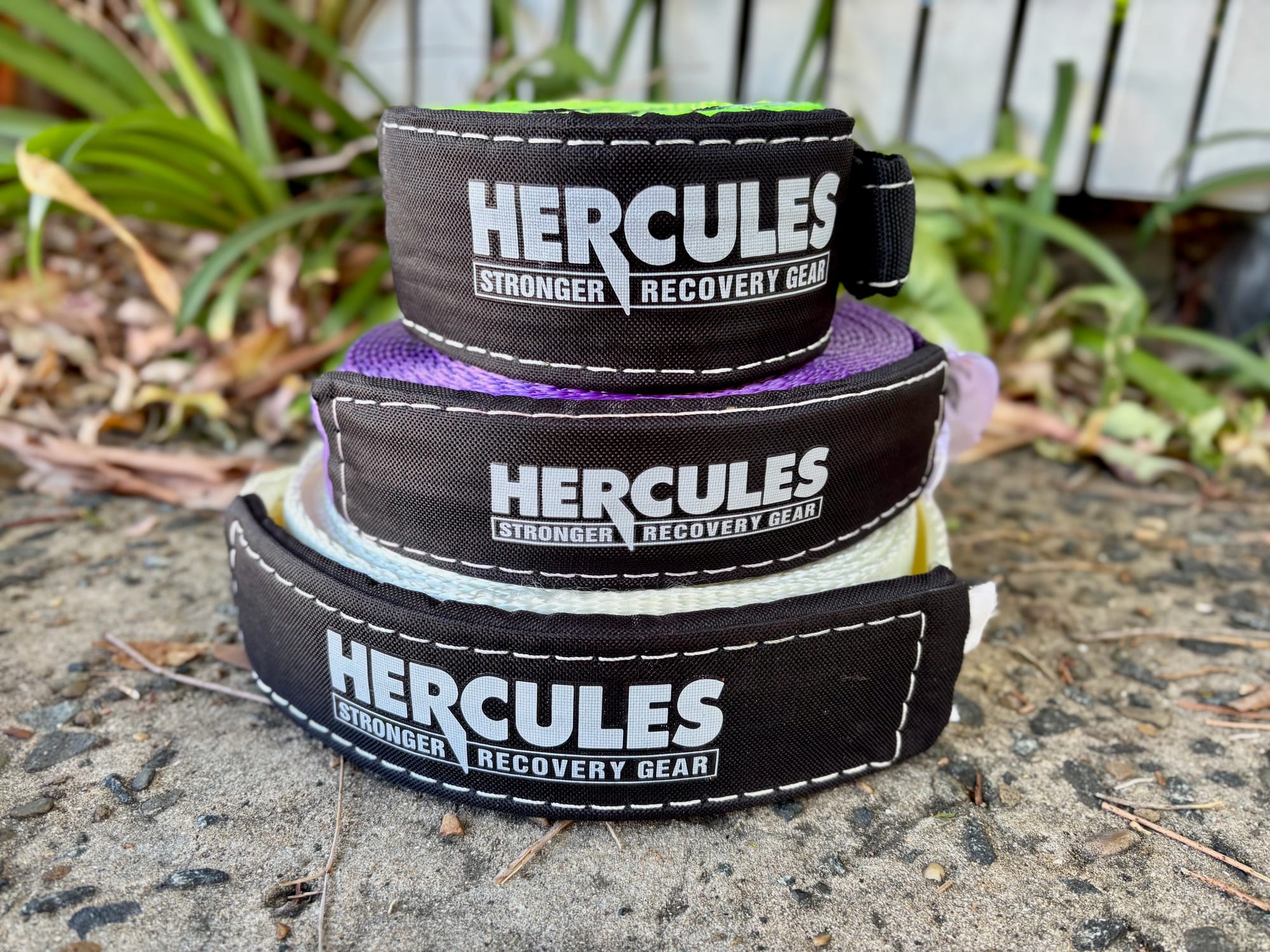 Three rolled Hercules recovery straps stacked up: lime green, purple and white