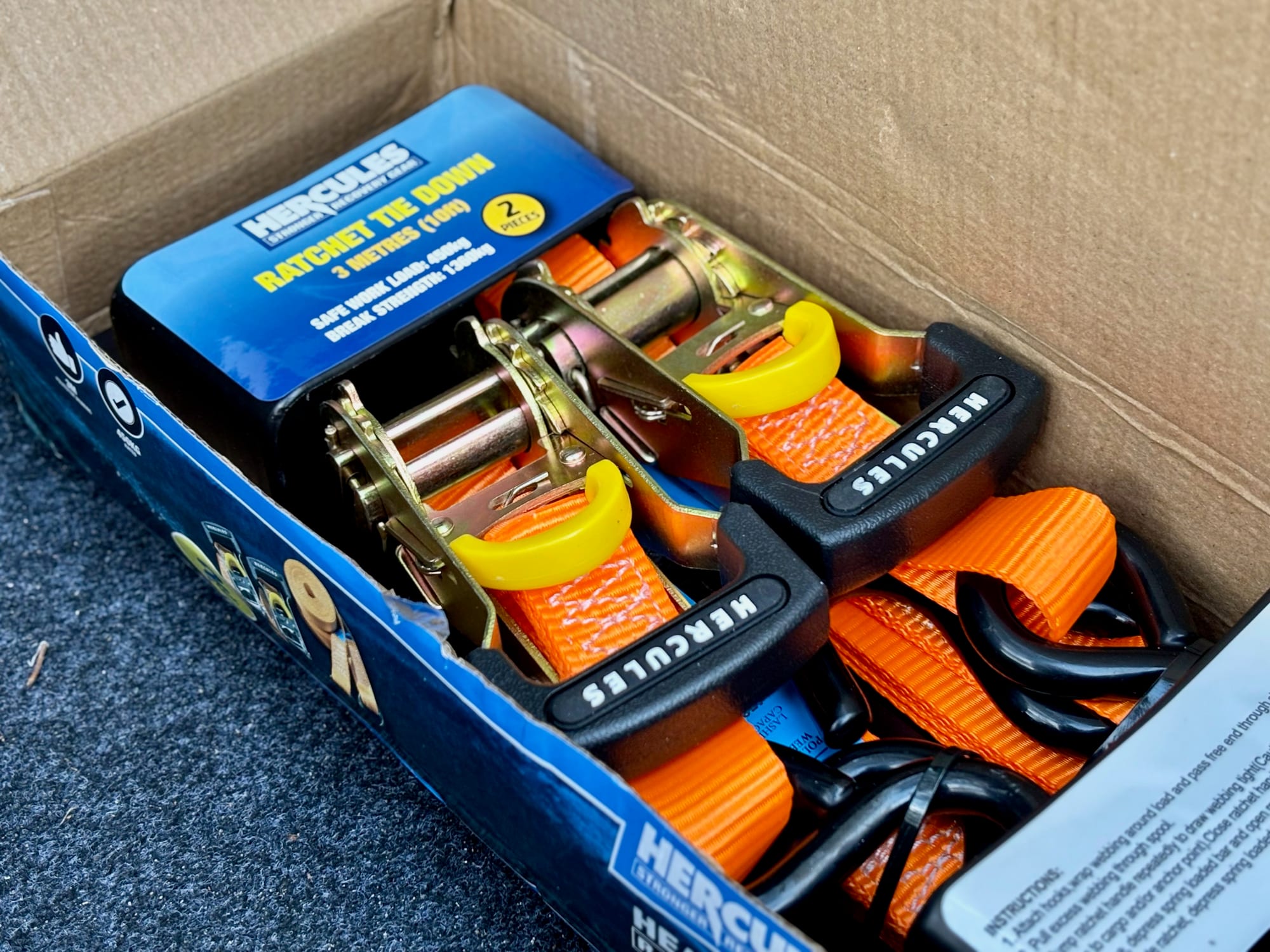 Two Hercules ratchets and orange straps on their card inside the open box