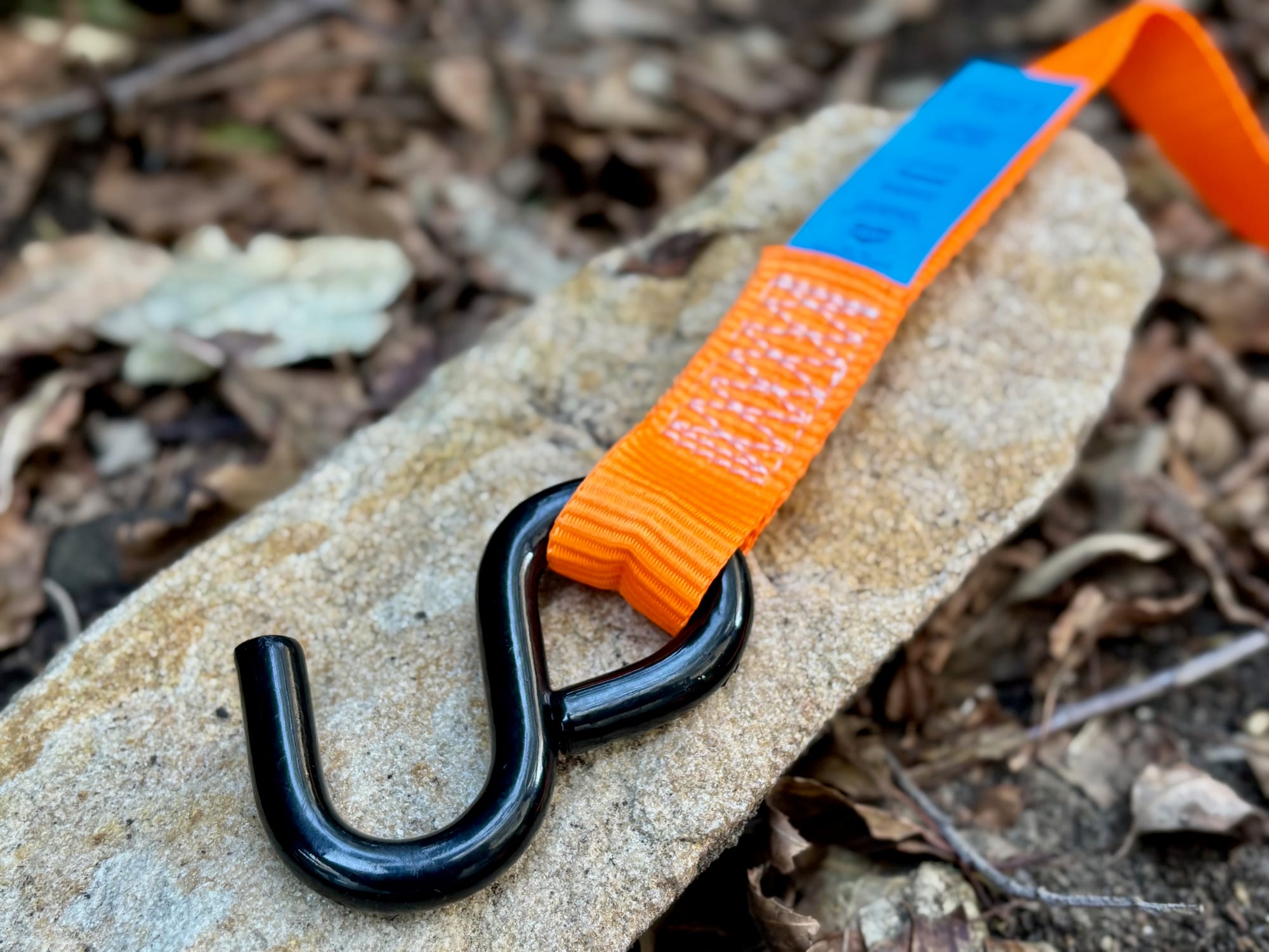 A black coated S-hook on the end of the orange webbing