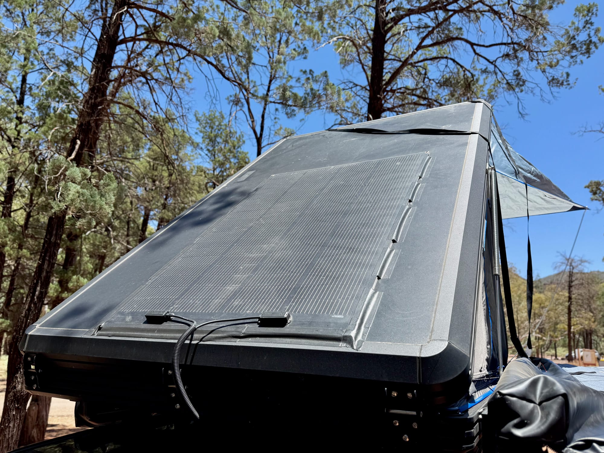 The flexible solar panel on the open rooftop tent, angled towards the sun