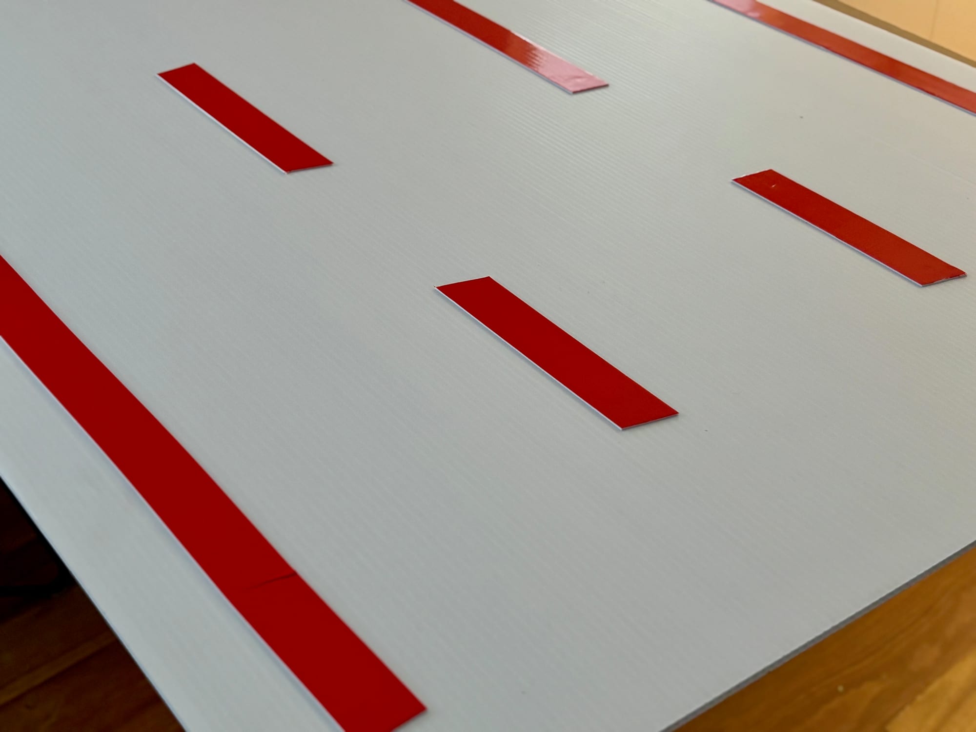 Strips of double-sided tape with red backing on the corflute