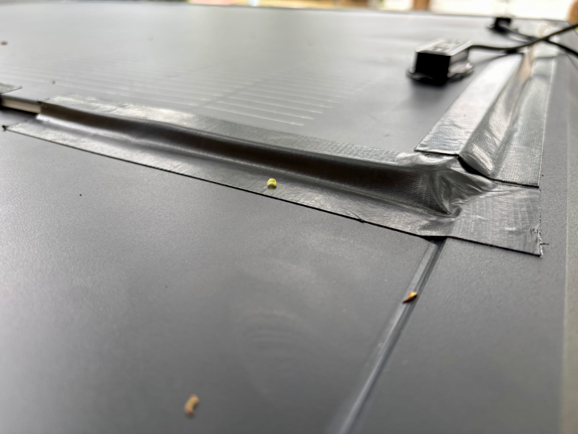 A taped corner of the flexible solar panel on the rooftop tent