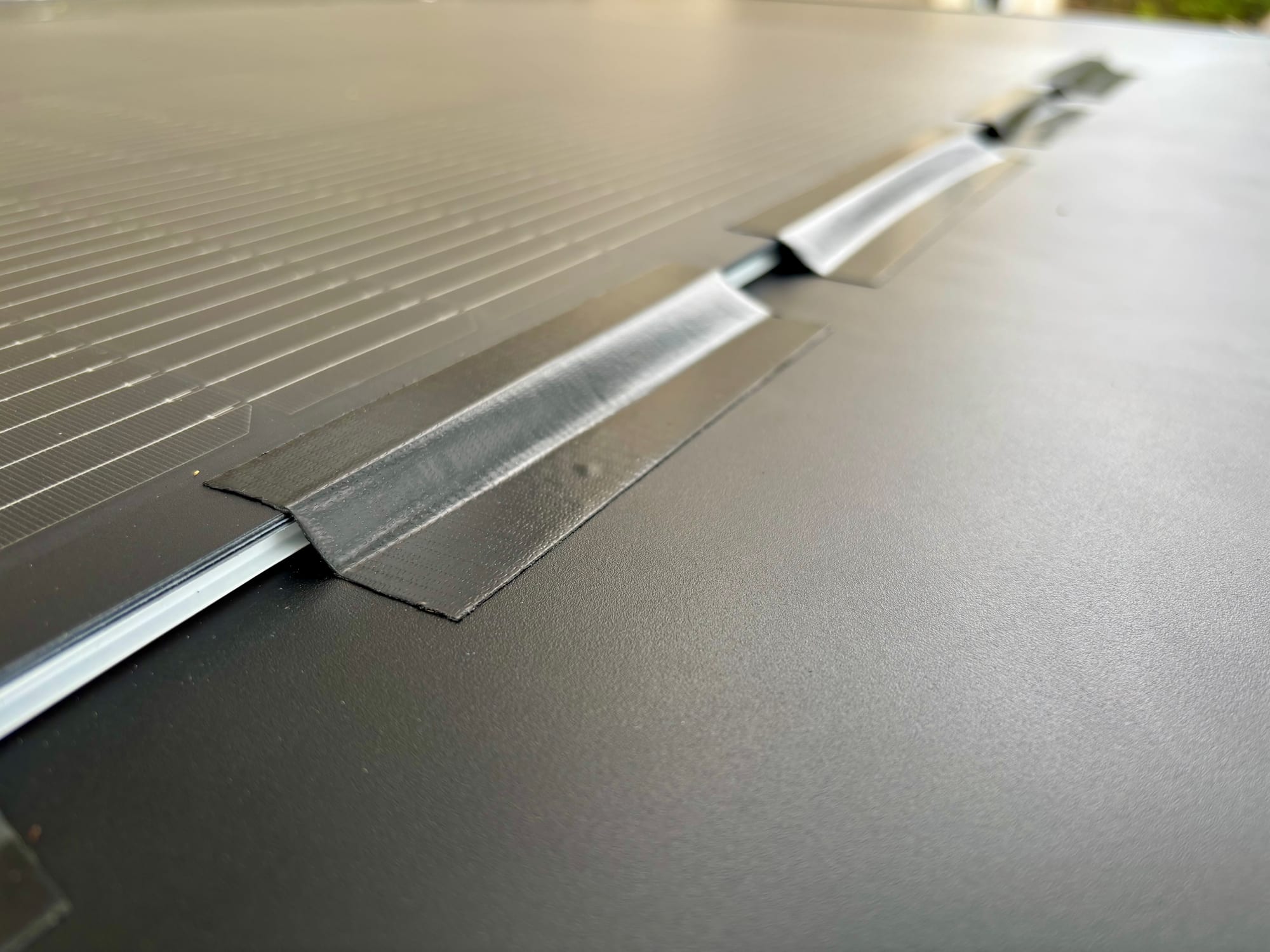Black tape along the edge of the flexible solar panel on the rooftop tent