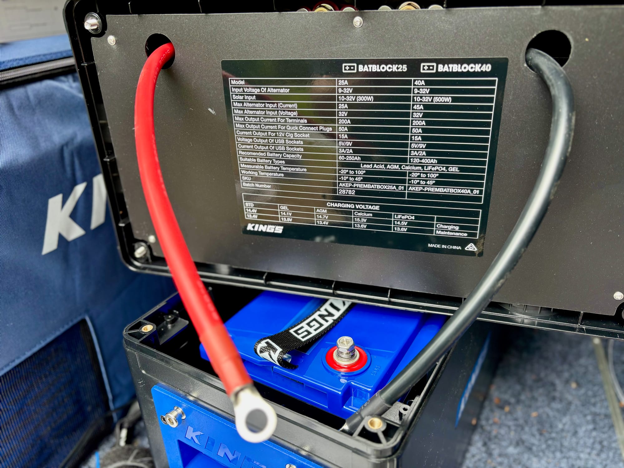The lid of a Kings BatBlock 25 lifted, with the red and black cables bolted to the terminals of the lithium battery inside