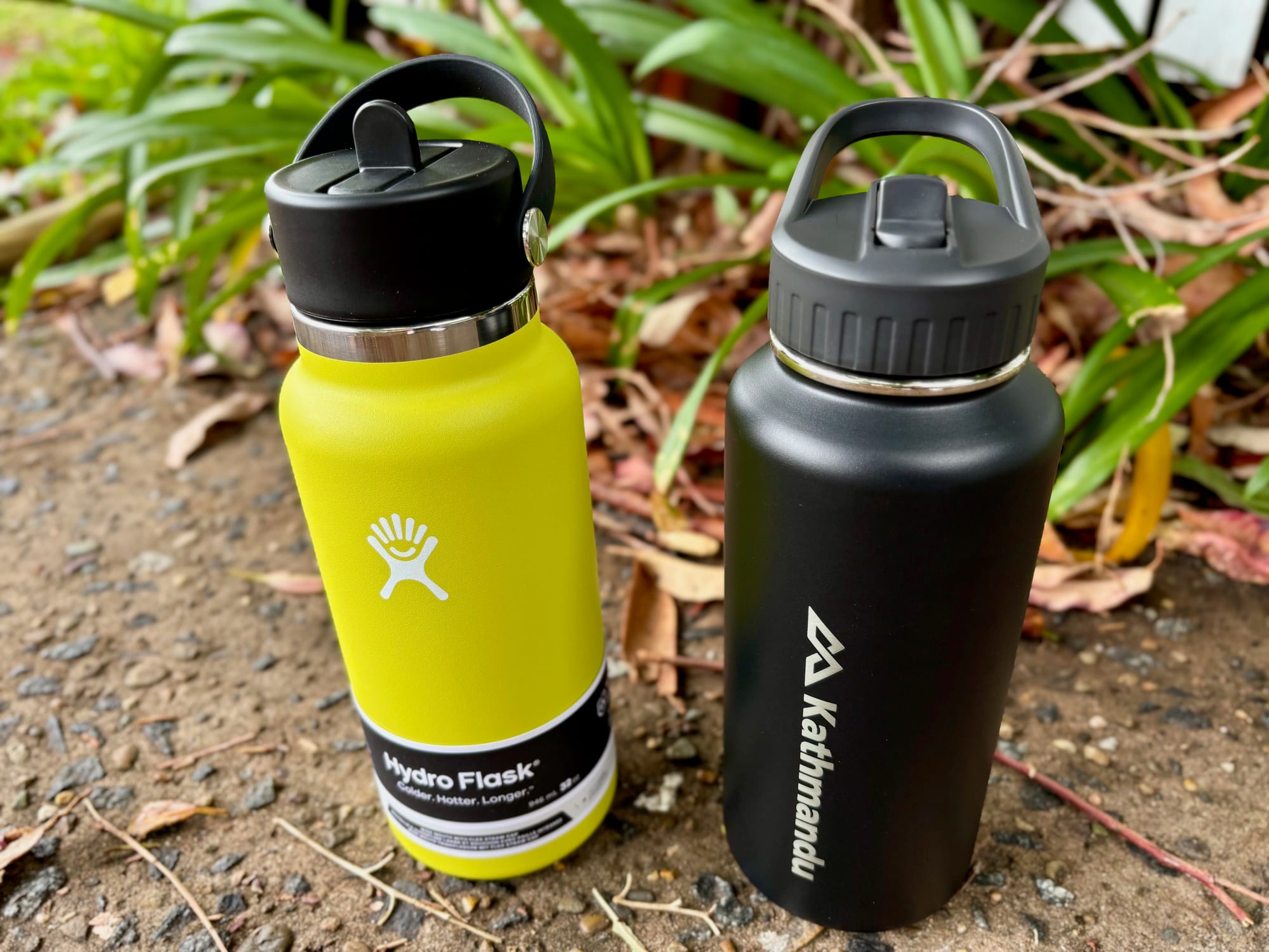 The Hydro Flask next to a Kathmandu insulated straw-lid bottle of similar size, both with their straws flipped up