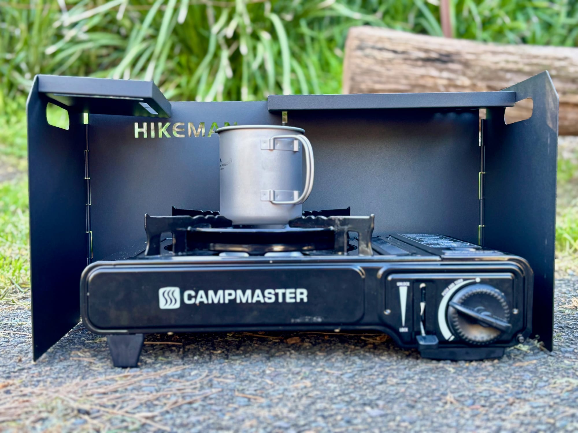 A titanium cup on a Campmaster butane stove, with a black windscreen around three sides