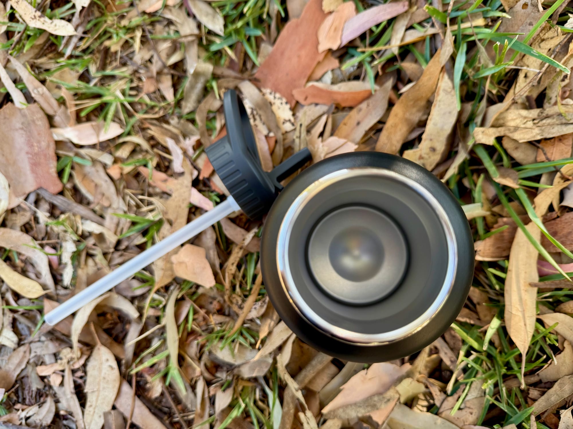 The wide stainless steel mouth of the Kathmandu bottle, with the lid and straw beside it