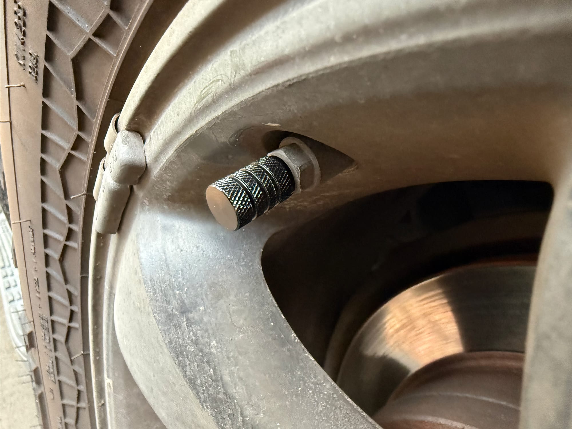 A KickAss brass valve cap screwed onto the tyre valve of a 4WD