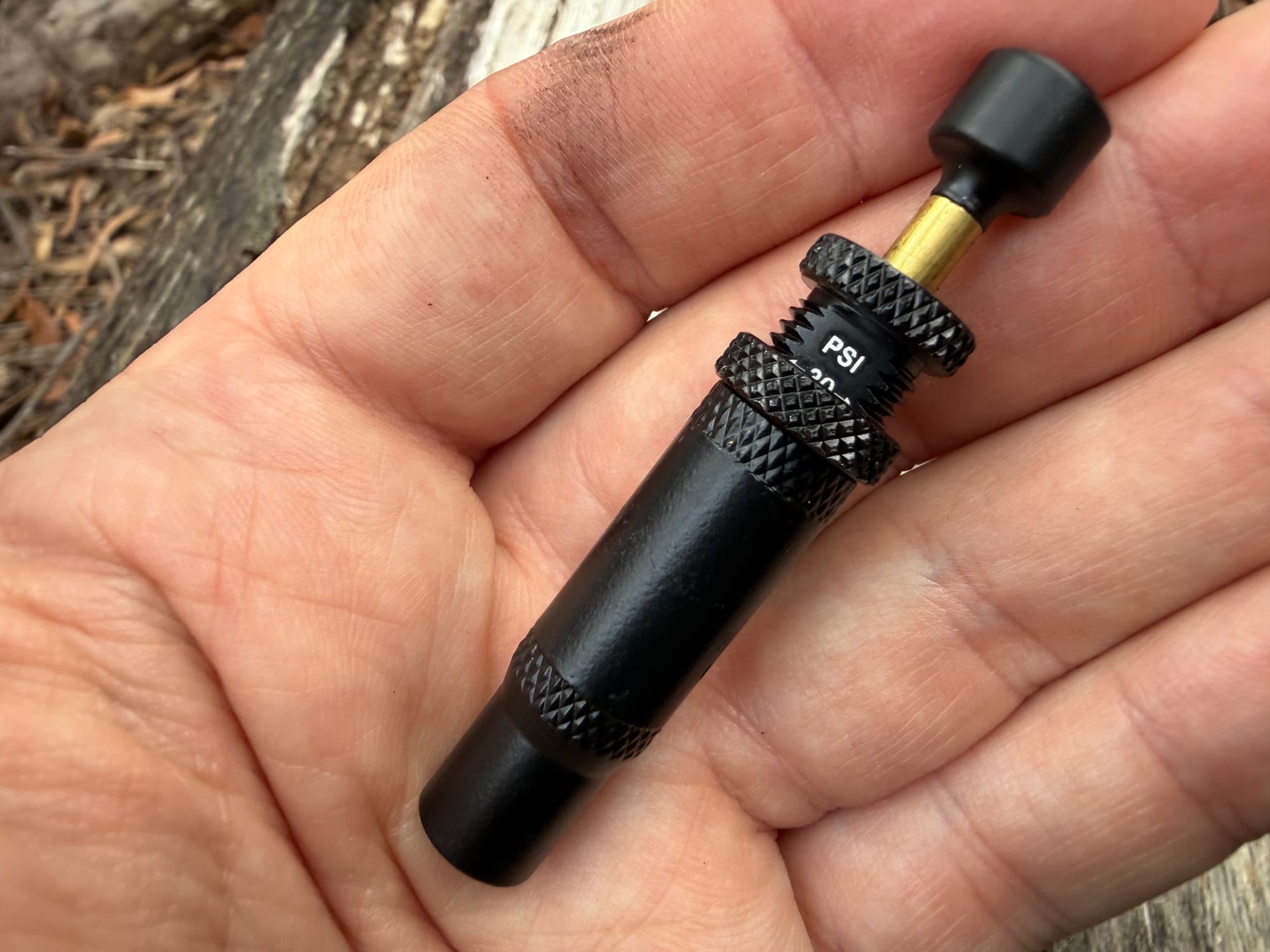 A KickAss deflator in a hand with the lock ring screwed back down against the body at 20 PSI