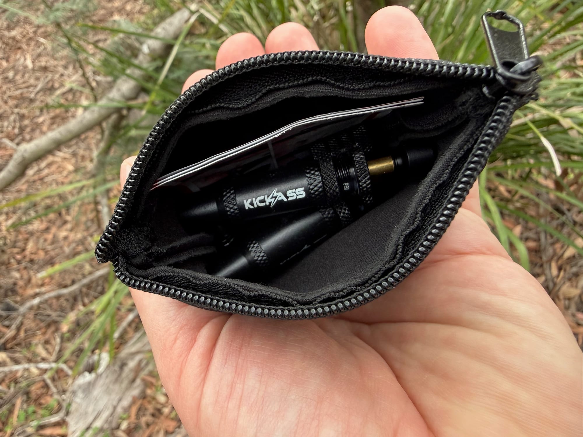 Four KickAss tyre deflators in an open black zip pouch, held in a hand