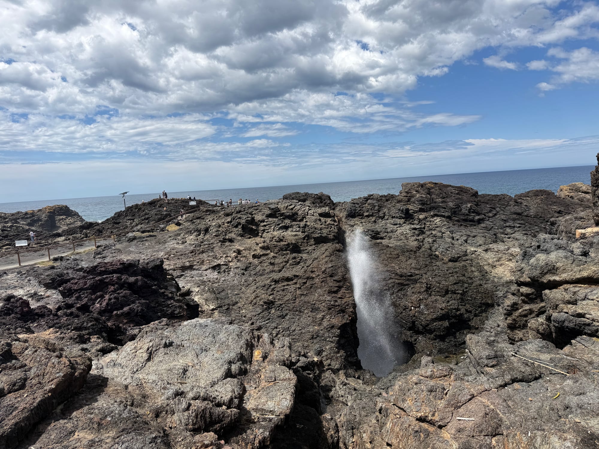 Water shooting up from the Kiama Blowhole between dark rocks