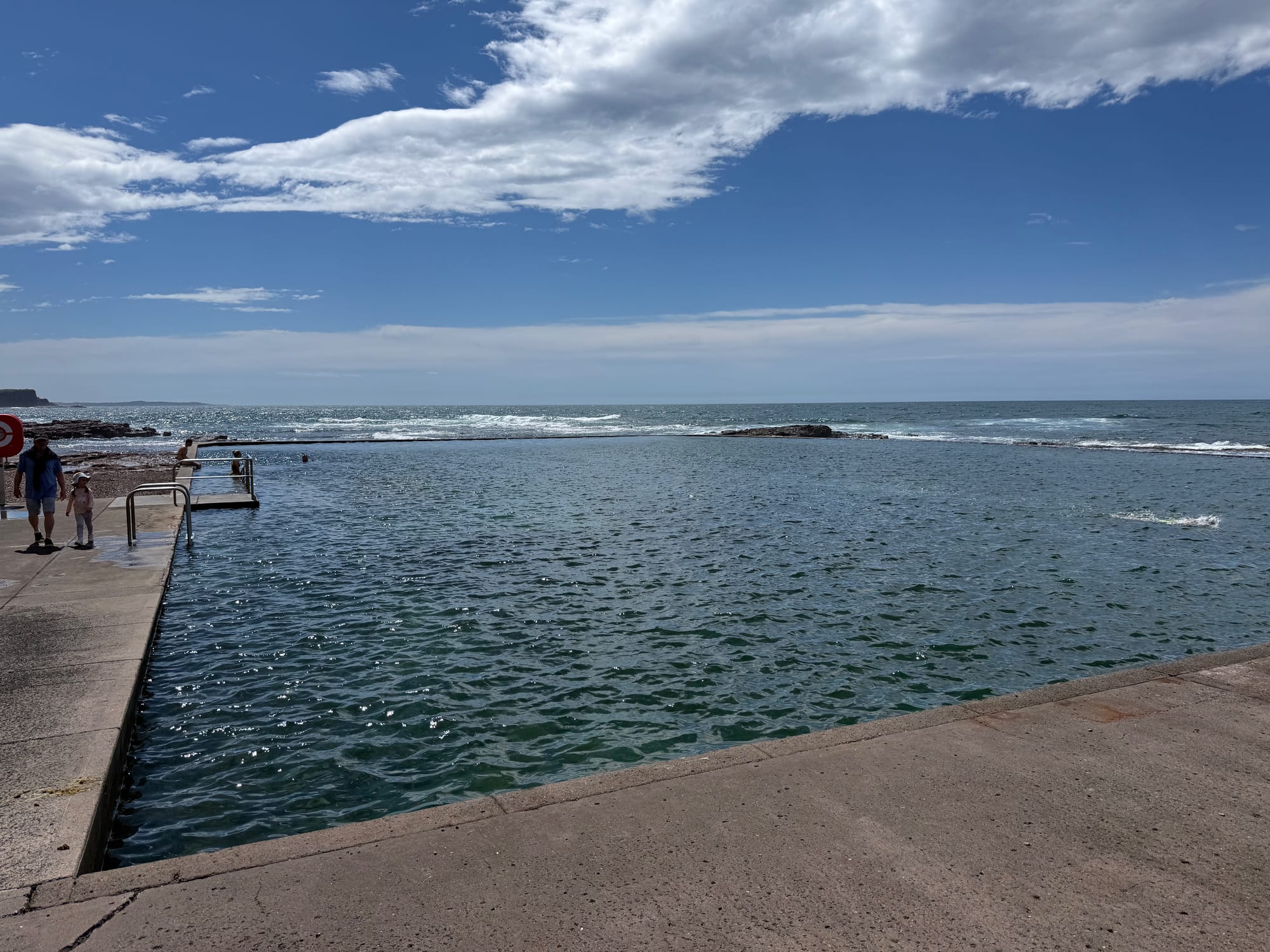 The Kiama ocean pool on the rocks by the sea, under a blue sky