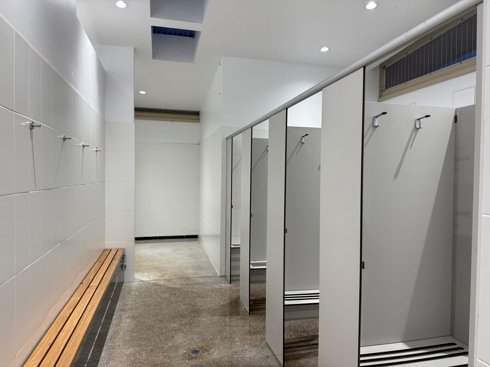 The shower cubicles in the amenities block at Killalea Campground, with a wooden bench along the wall