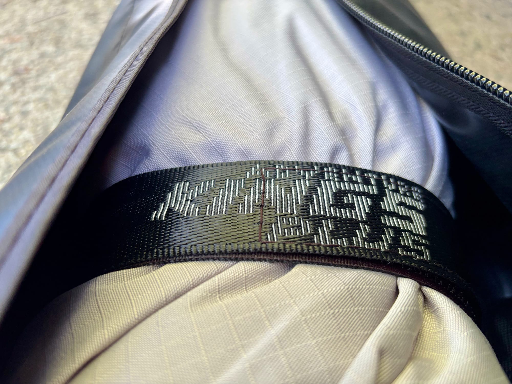A black Kings Plus strap holding the rolled-up grey canvas inside the cover