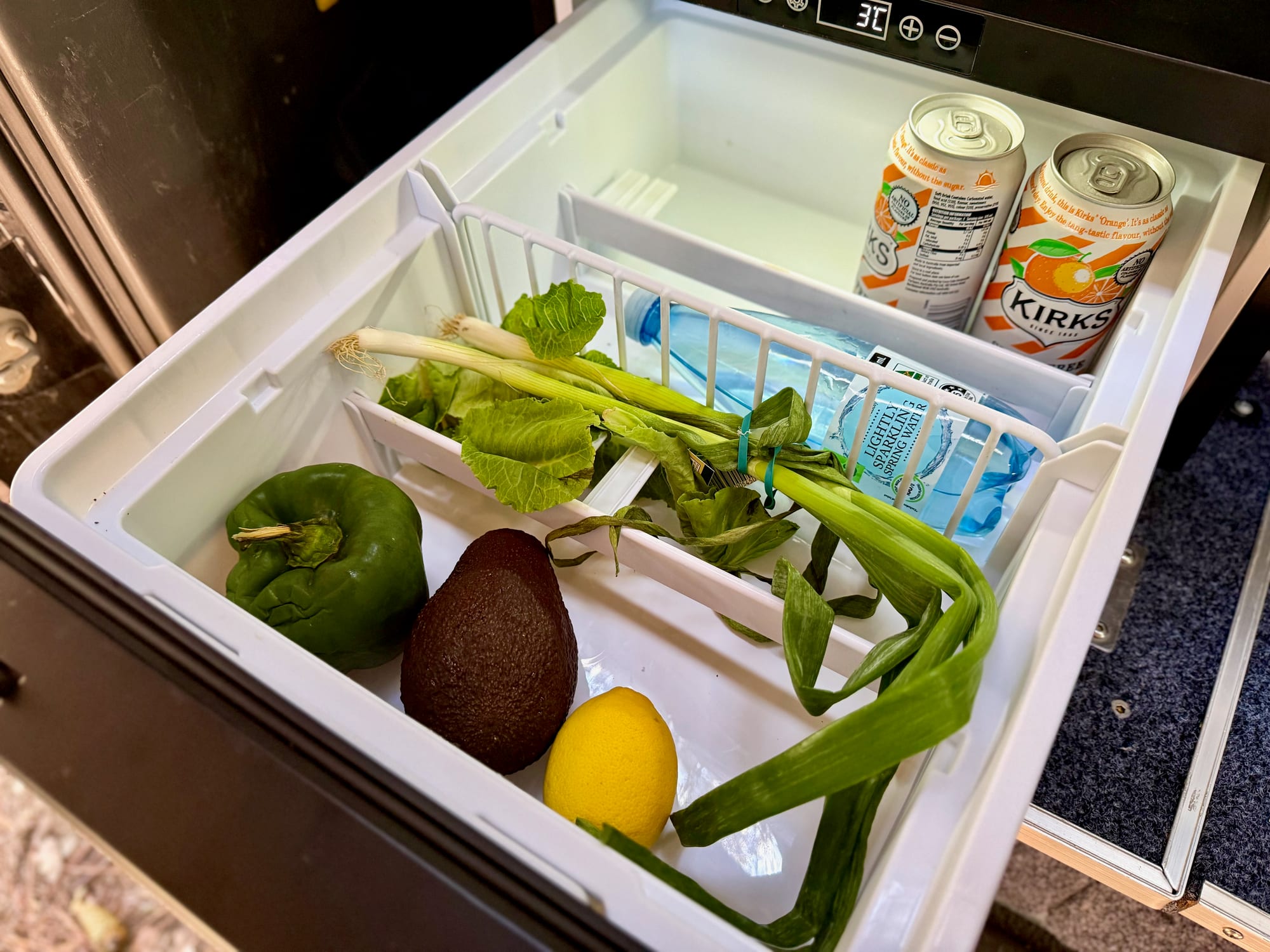 Looking down into the open Kings 30L drawer fridge: vegetables, cans and a water bottle in the basket