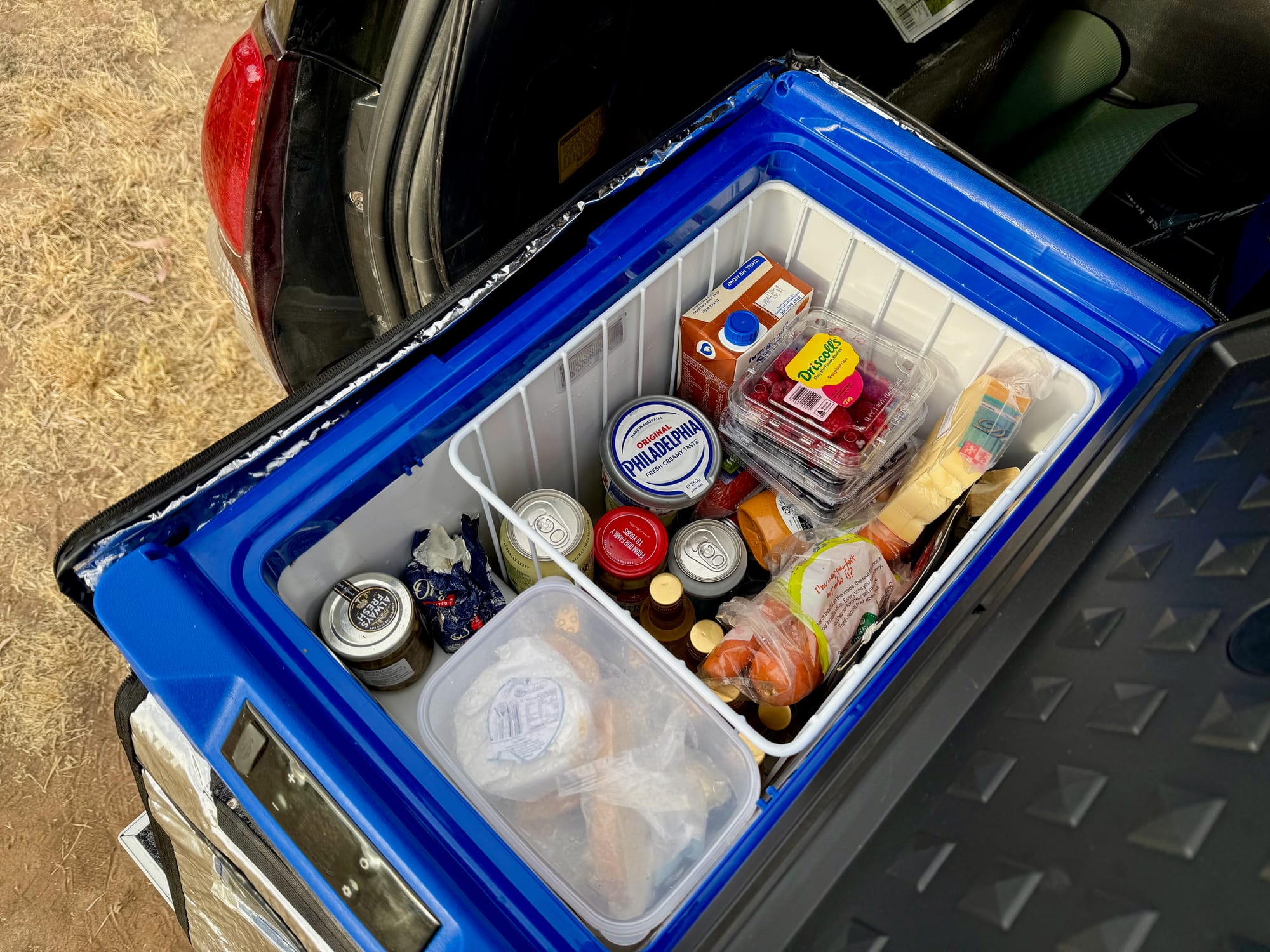 The Kings Escape 40 fridge open in the back of a Prado, packed with food, drinks and a container