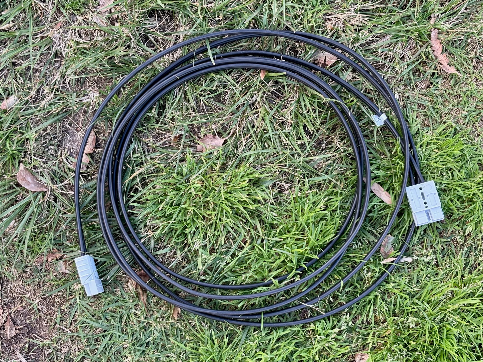 The Kings 6 m solar extension lead coiled on the grass, with a grey plug at each end