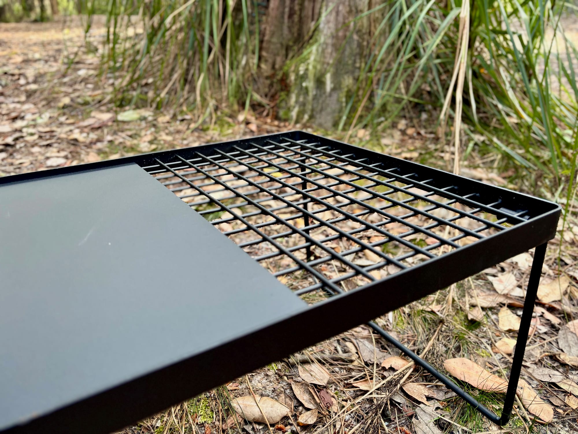 Close-up of the Kings Camp Fire BBQ Plate: the solid hotplate, the mesh grill and the raised lip around the edge