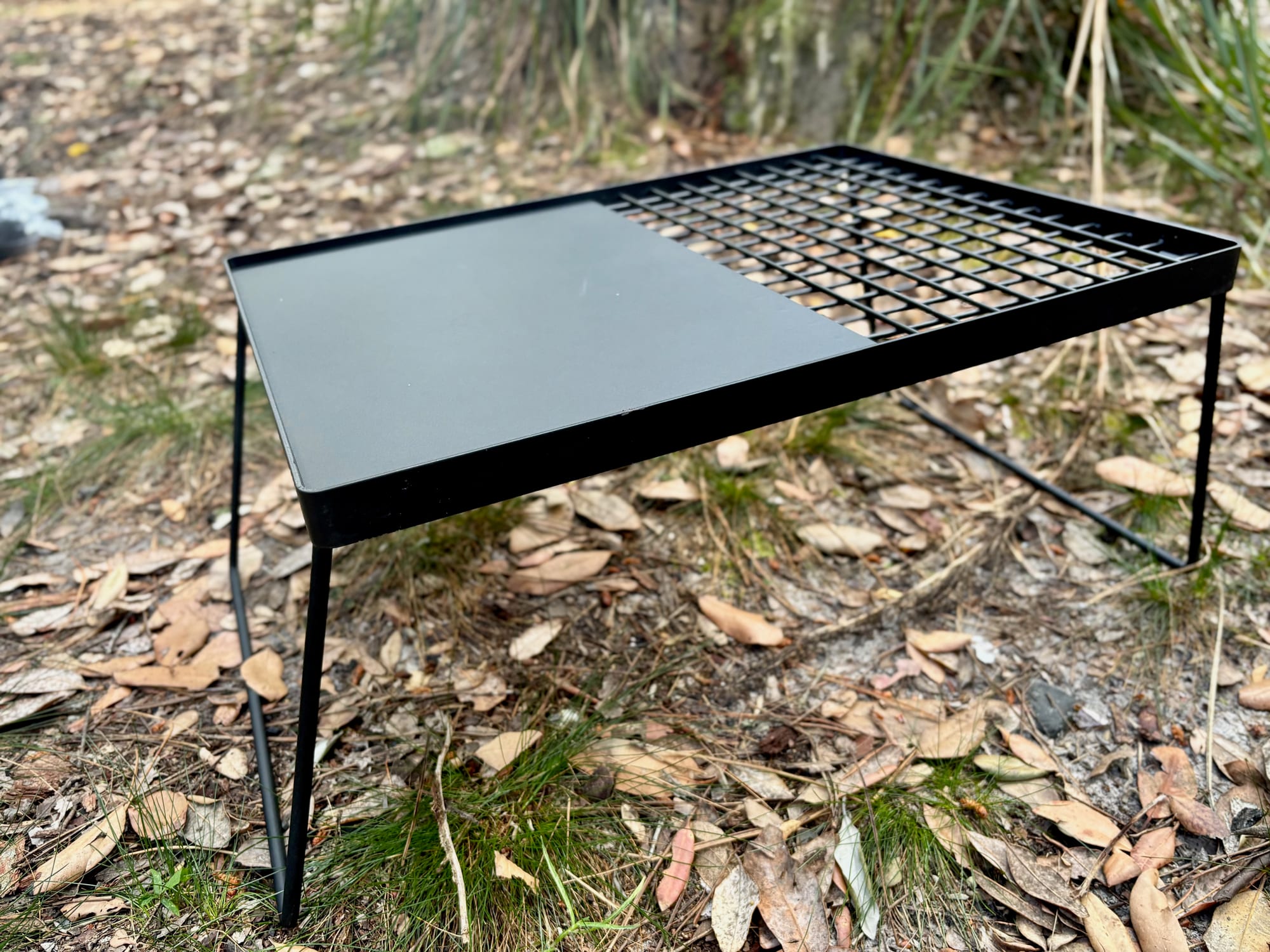The Kings Camp Fire BBQ Plate standing on its folding legs, with the hotplate on the left and the grill on the right