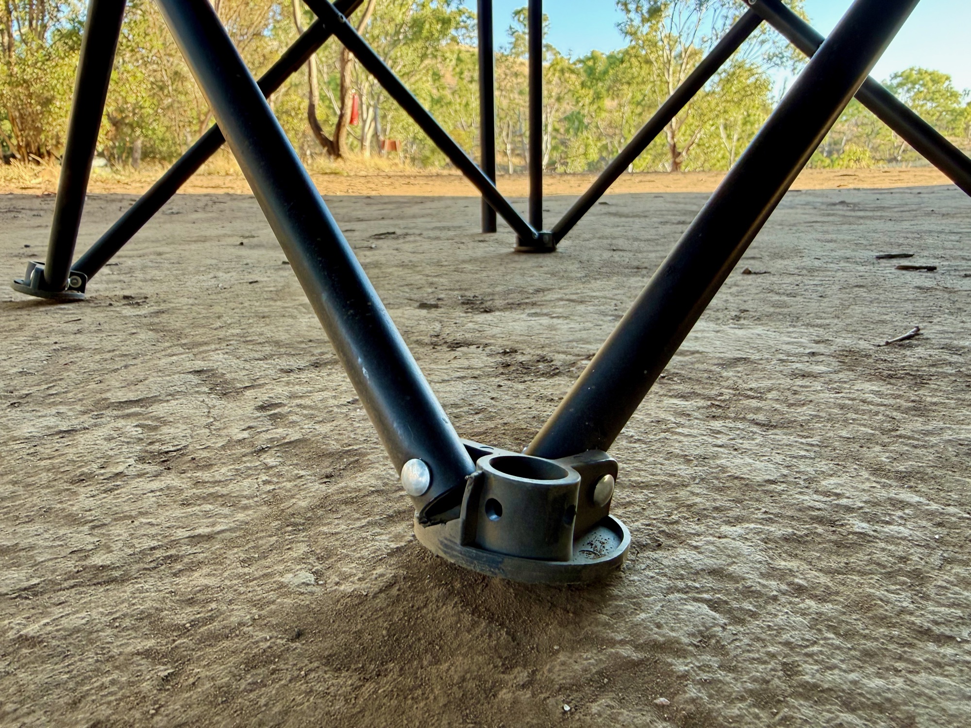 Close-up of the Kings Essential chair’s round foot where two frame tubes meet, on dirt at camp