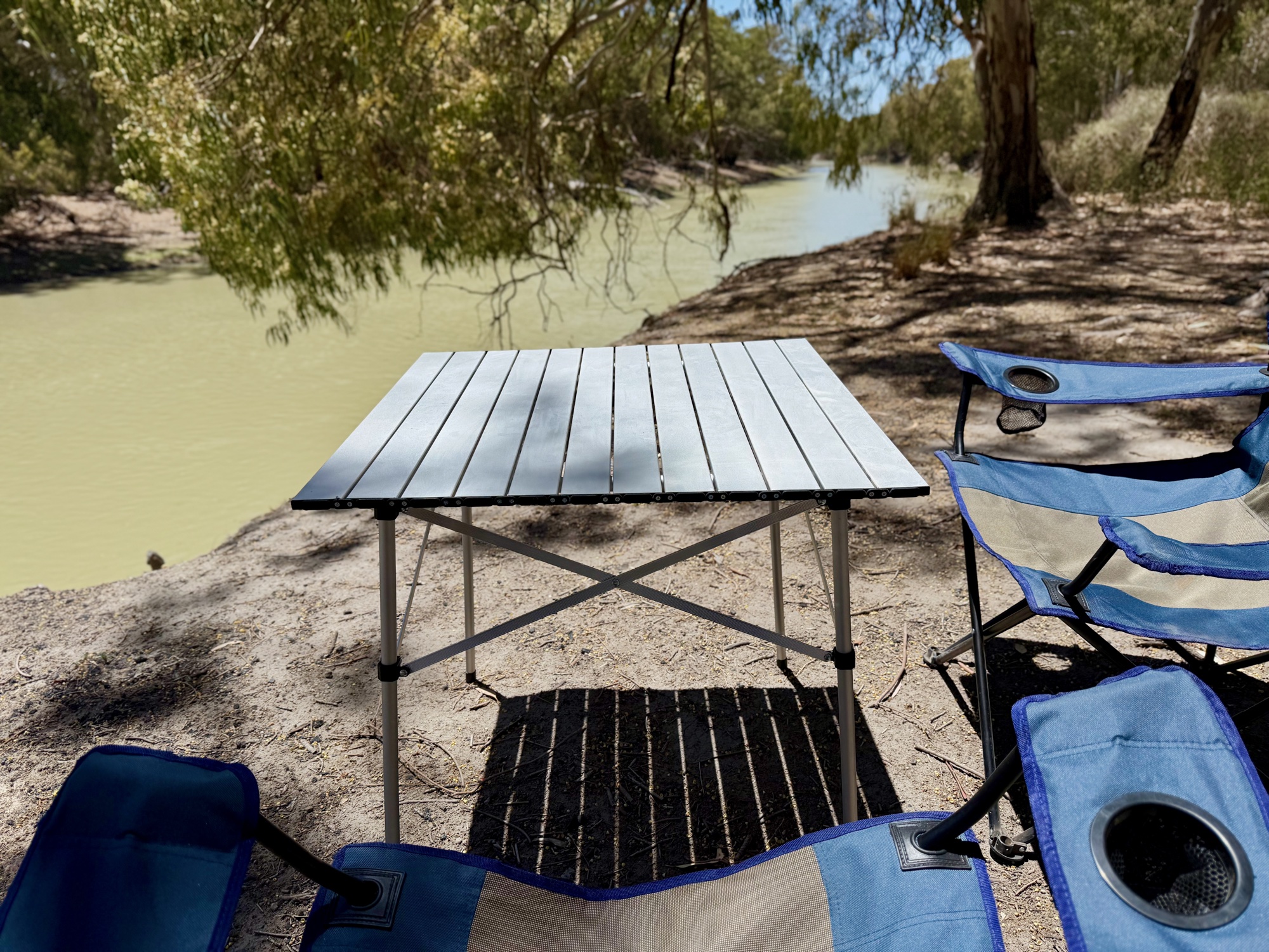 A Kings Essential chair pulled up to the Spinifex aluminium camp table by the river