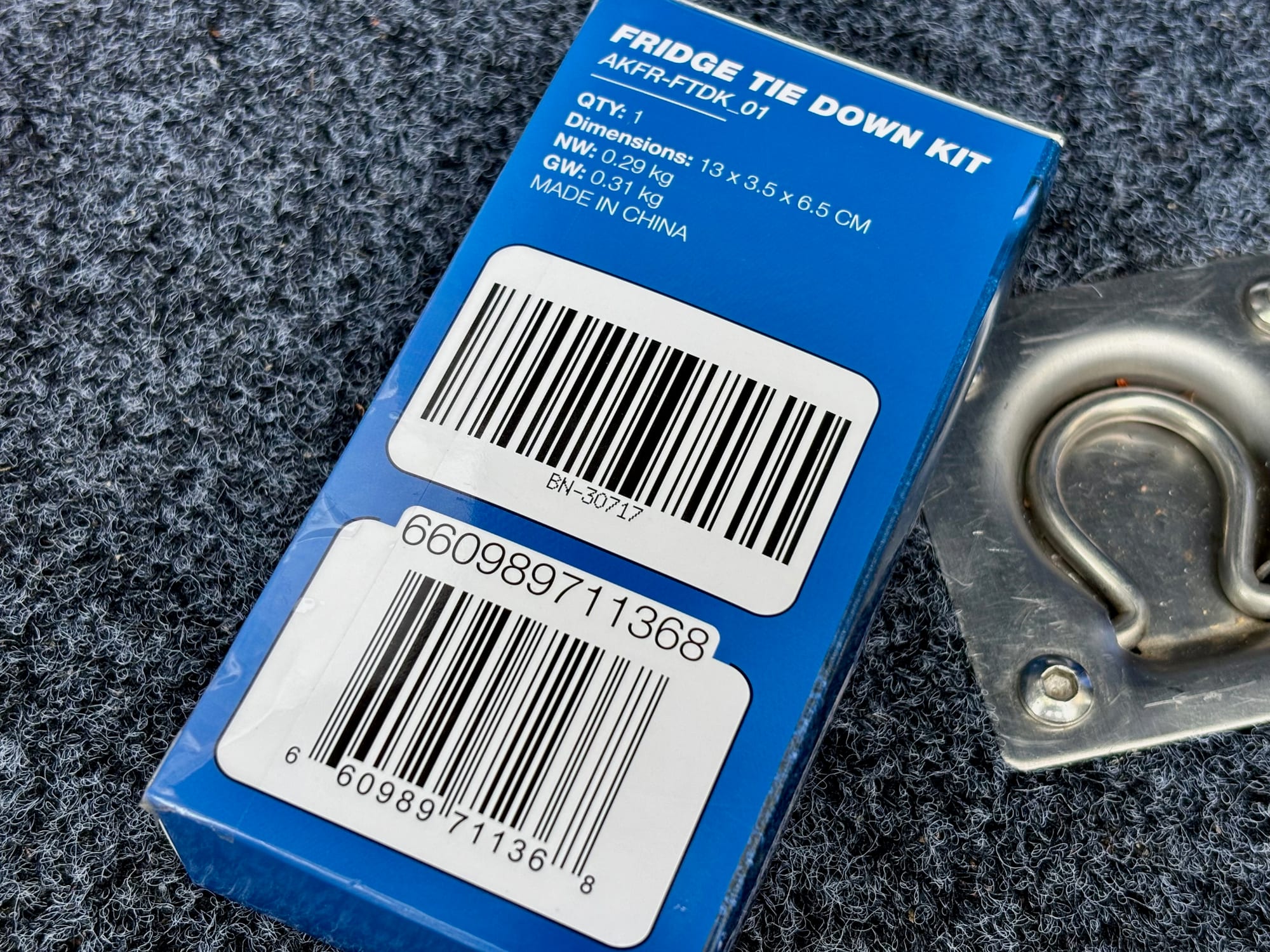 The box of the Kings fridge tie-down kit, model AKFR-FTDK_01, next to a tie-down ring