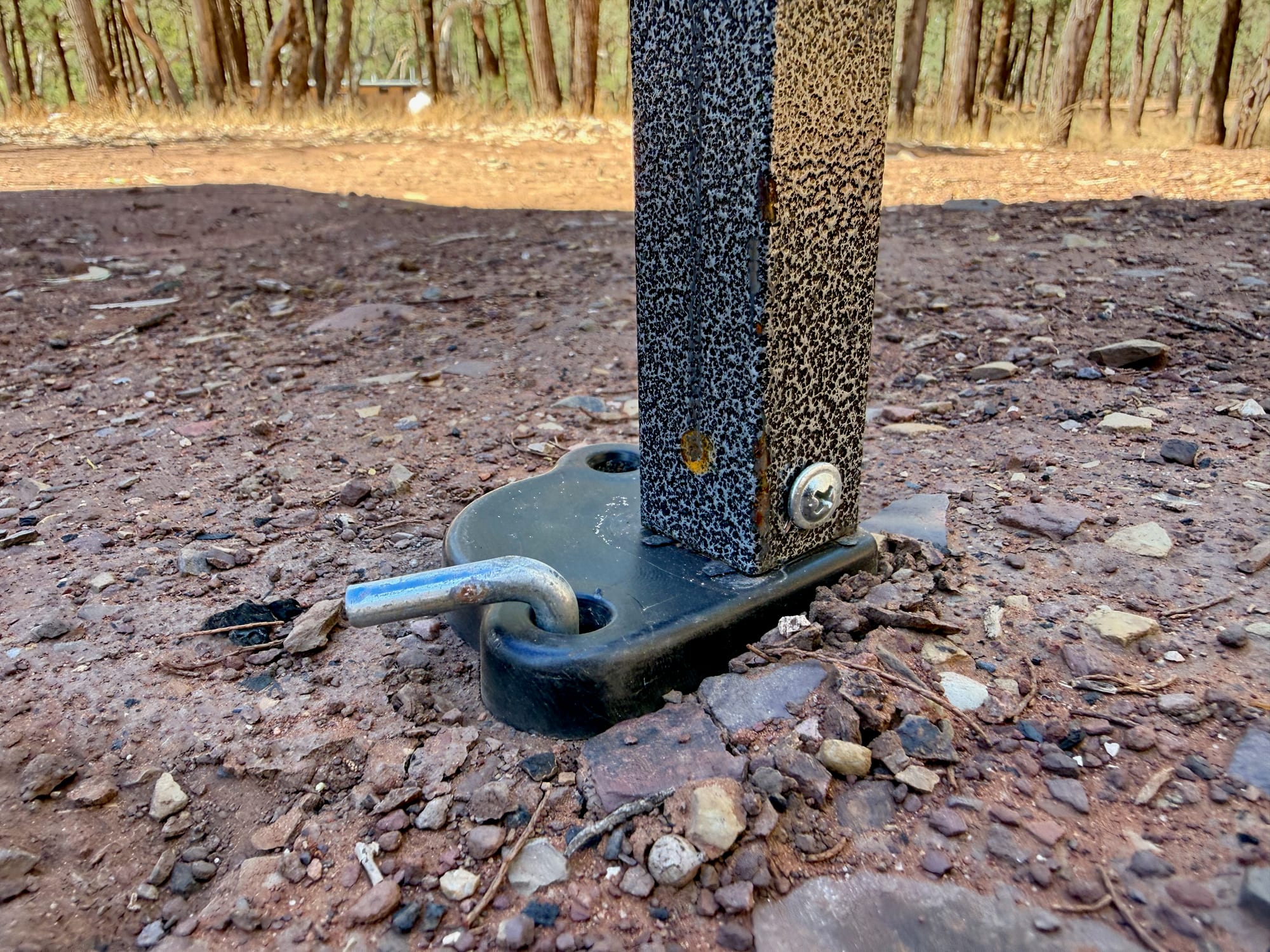 A Kings gazebo foot plate pegged into rocky red dirt