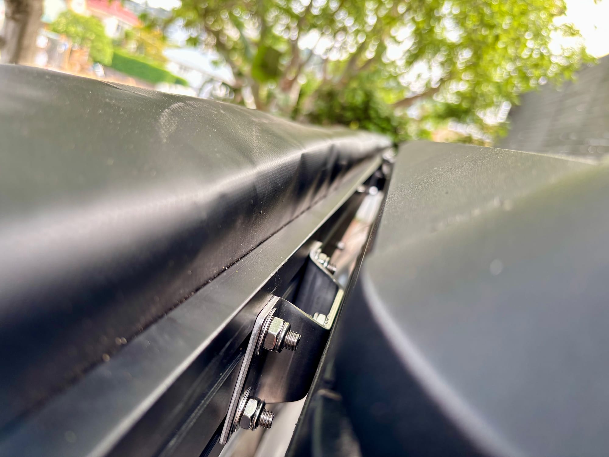 The awning mounted along the side of a Kings rooftop tent with stainless brackets between them