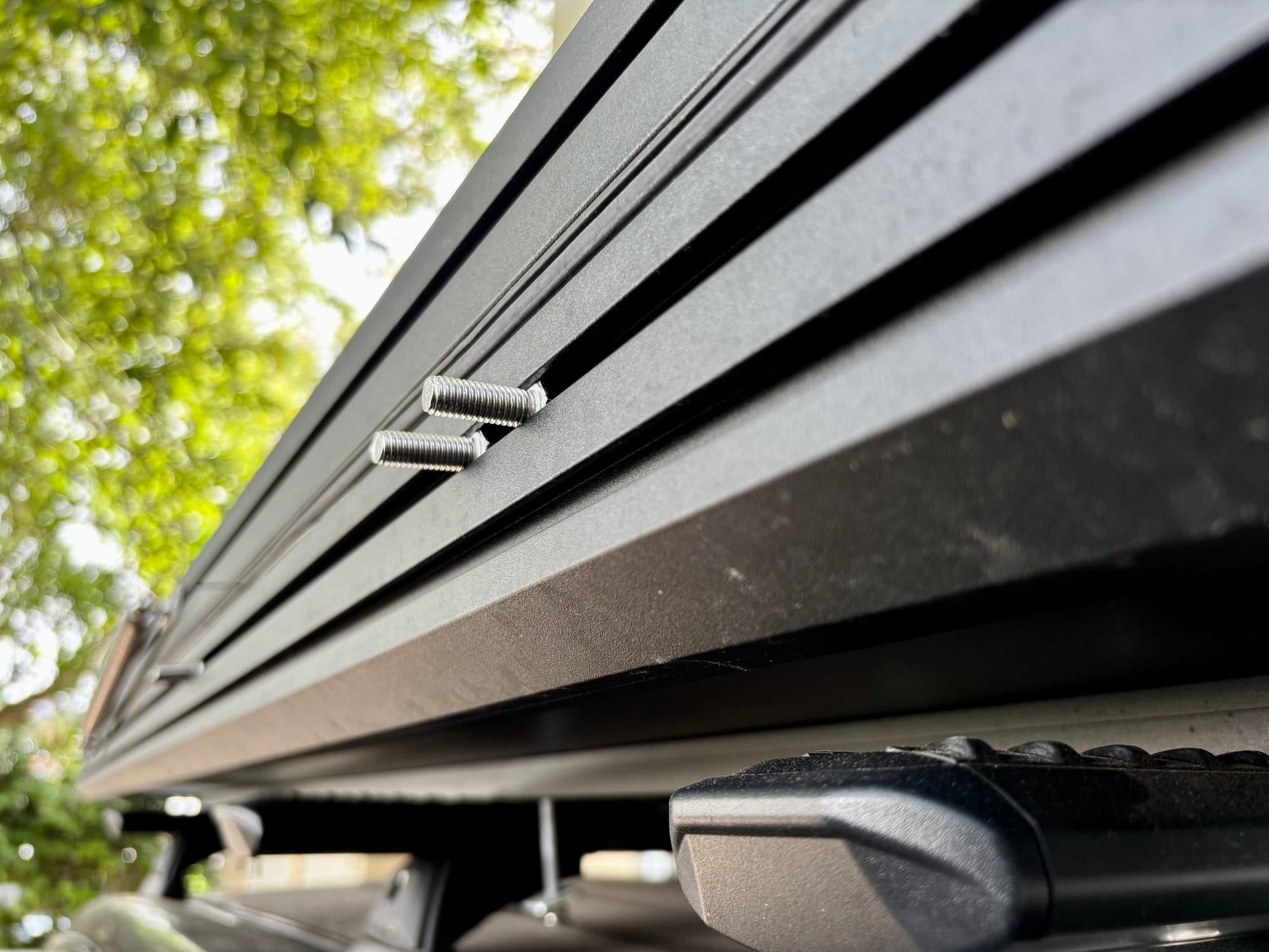 Two bolts slid into the accessory track on the side of a Kings rooftop tent