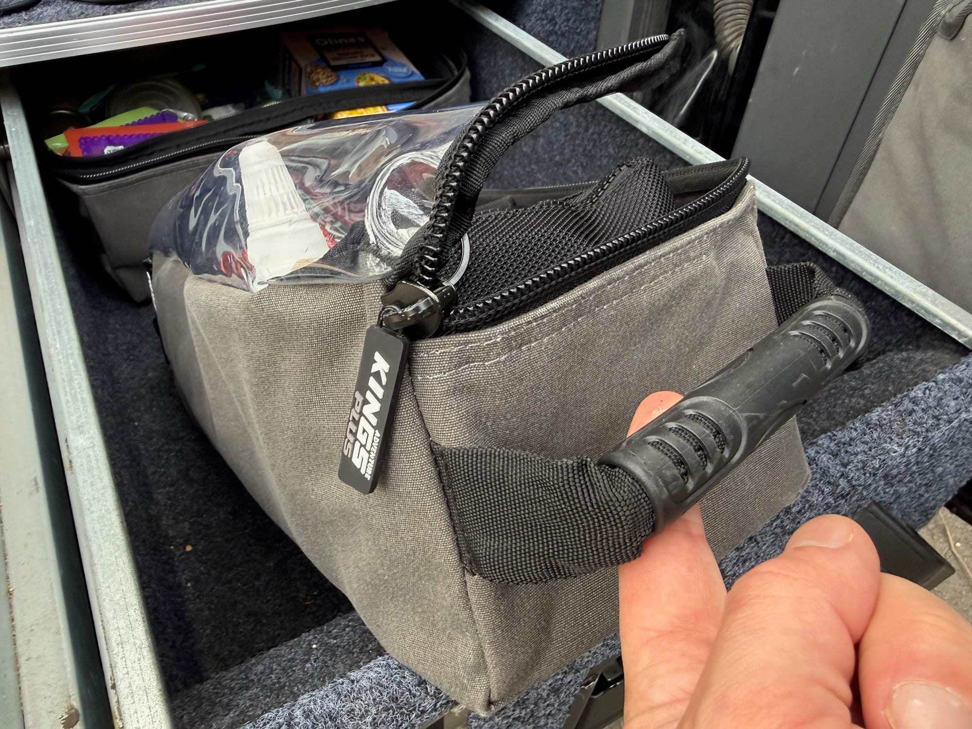 A hand lifting a Kings Plus bag by its moulded rubber side handle