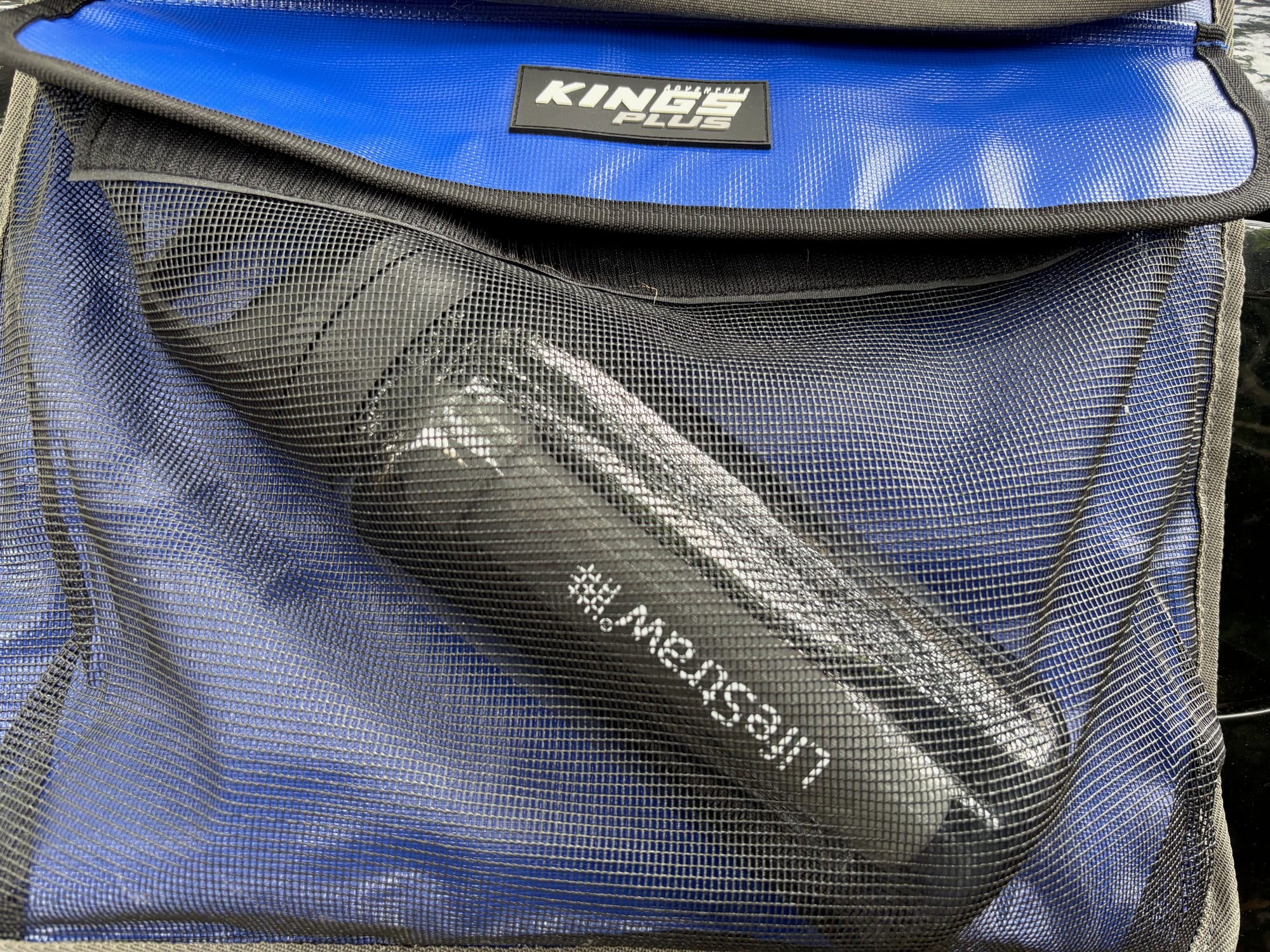 The lower pocket of the Kings Plus Hanging Camp Caddy with its blue fold-over flap and mesh front