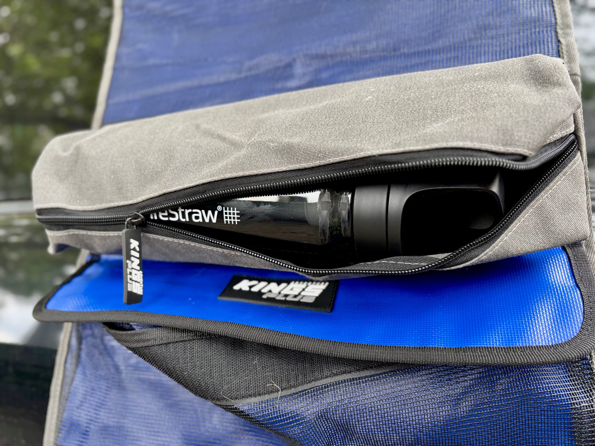 The removable grey zip bag of the Kings Plus Hanging Camp Caddy, open with a water bottle inside