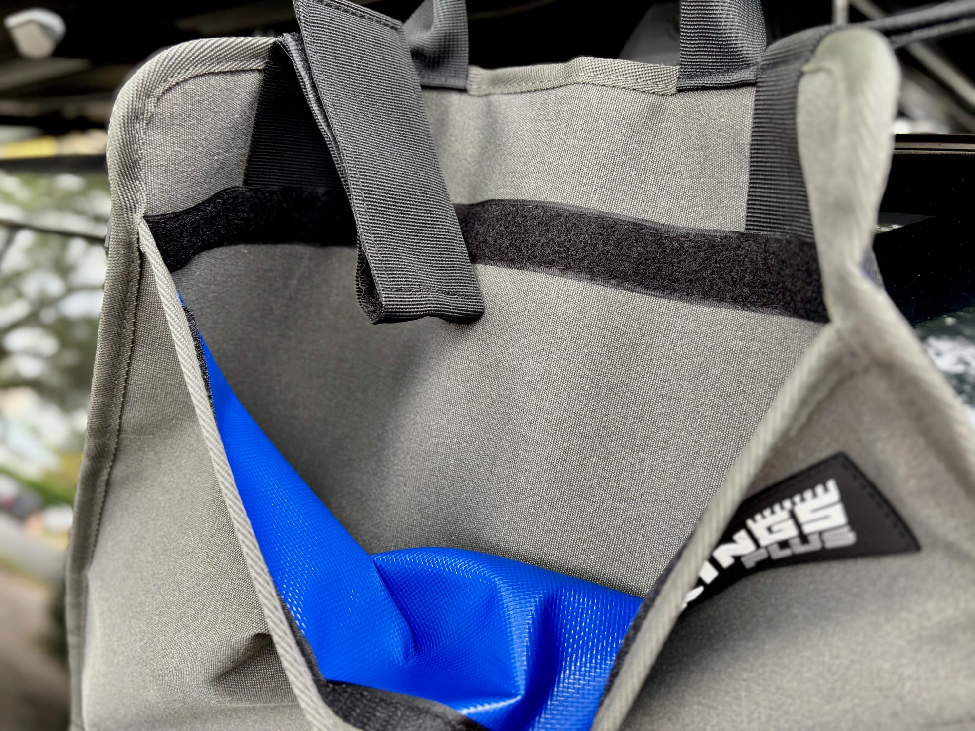 The sleeve pocket on the back of the Kings Plus Hanging Camp Caddy pulled open, showing the grey canvas outside and the blue PVC lining inside