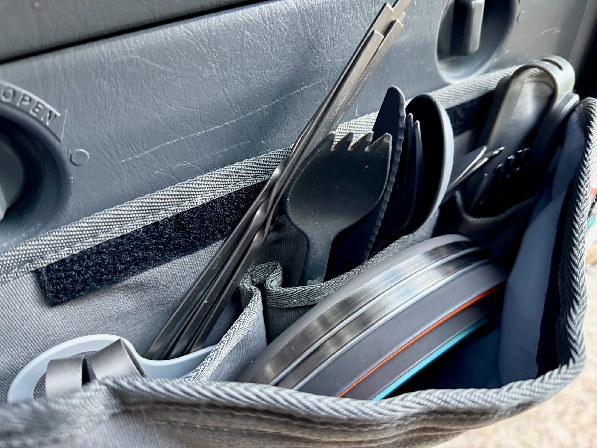 Camp cutlery, tongs and stacked plates in the Kings Plus Pocket Organiser on the tailgate