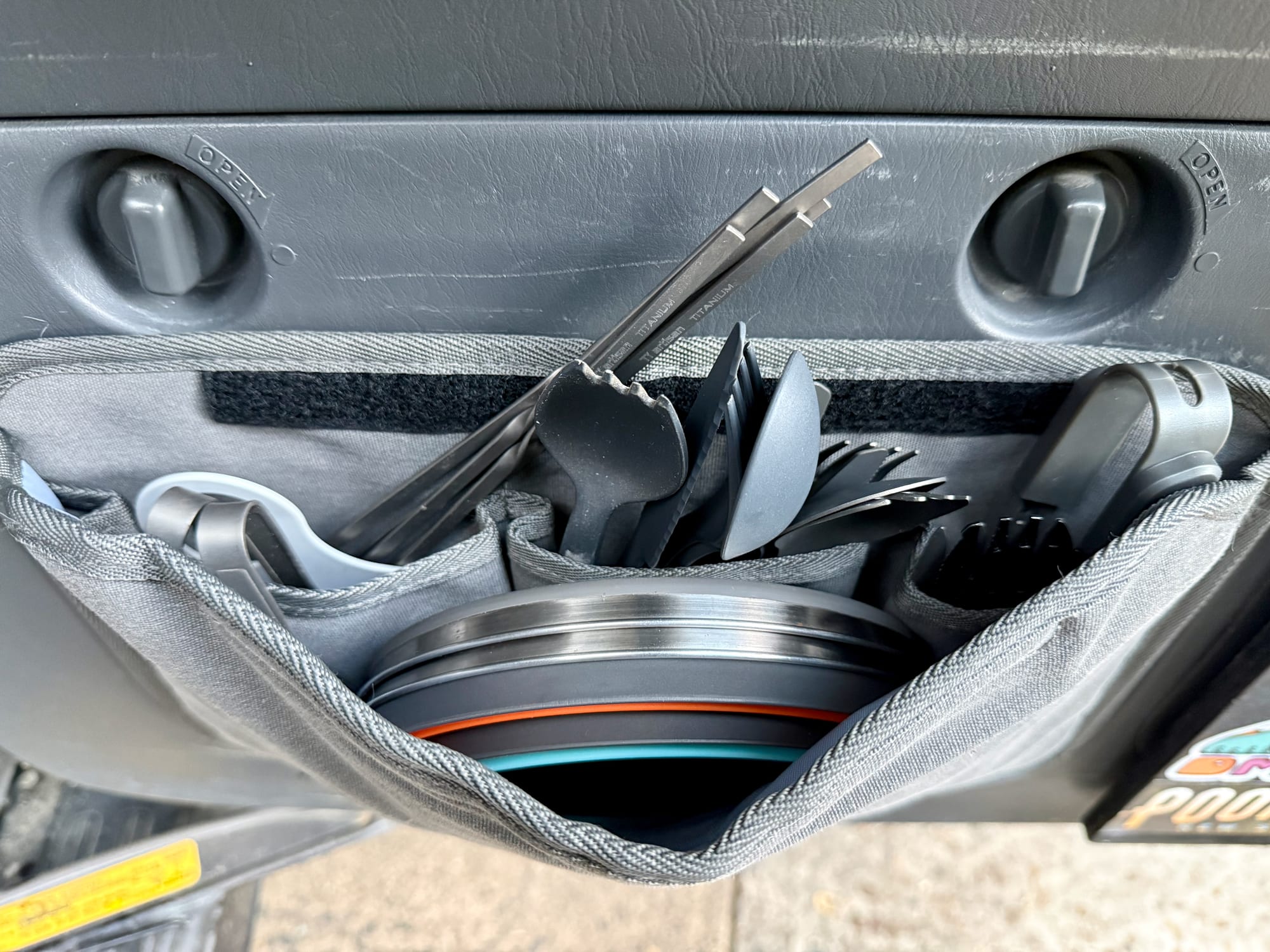 The Kings Plus Pocket Organiser on the inside of a 4WD tailgate, open and full of cutlery and plates
