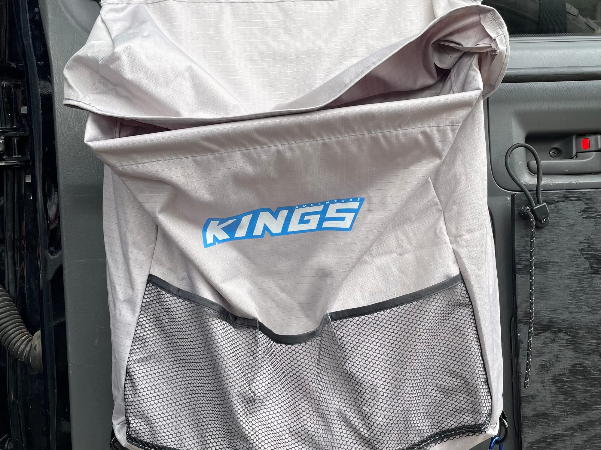 The Kings Universal Storage Bag hanging on the inside of a car door